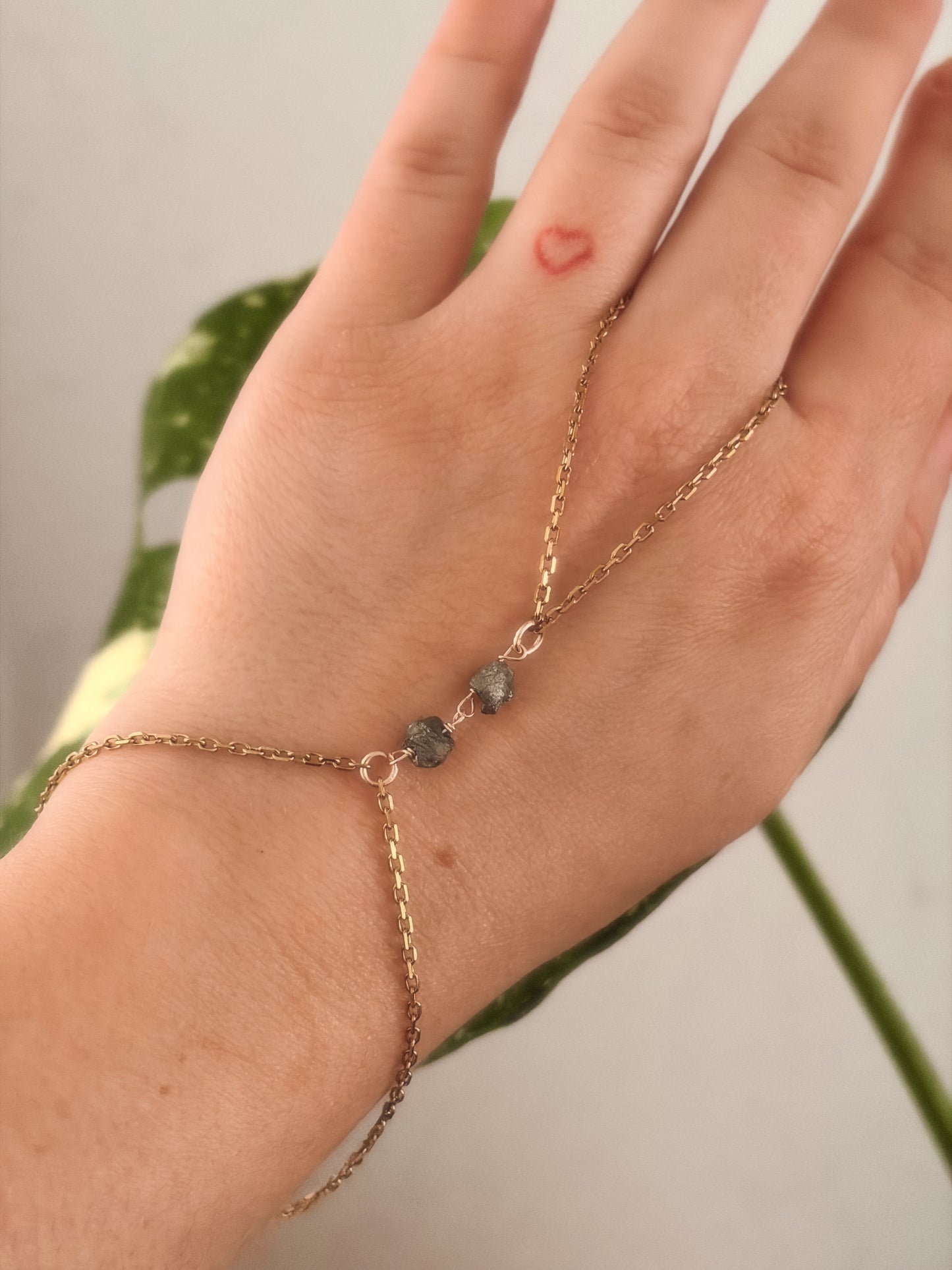 Hand wearing a gold stainless steel bracelet with raw pyrite stones.