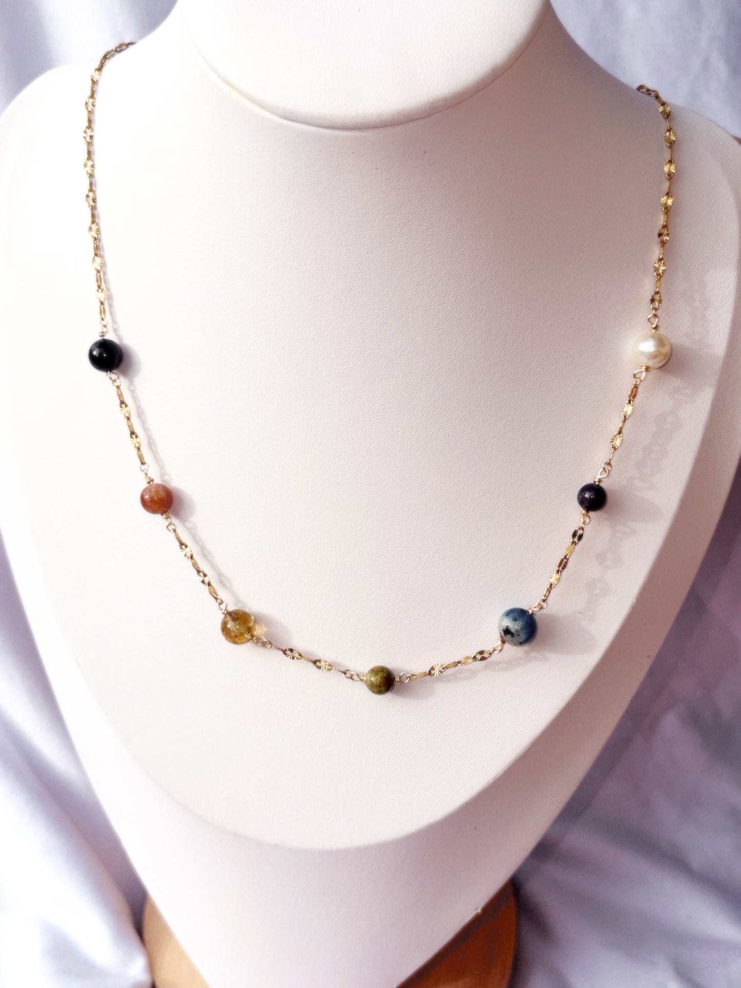 Gold Stainless Steel Necklace with colorful stones on a white stand
