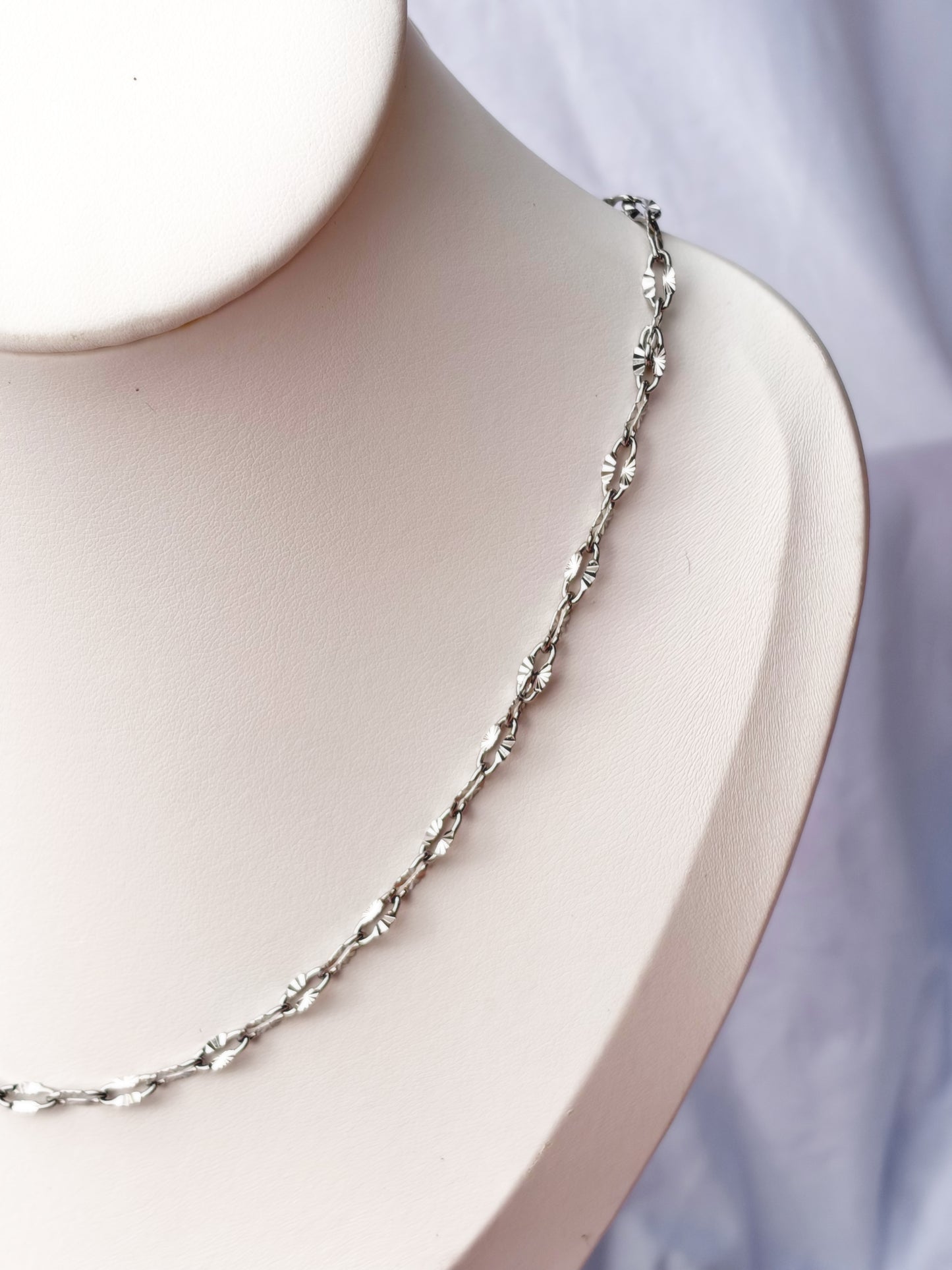 Silver necklace on a mannequin bust with a white background