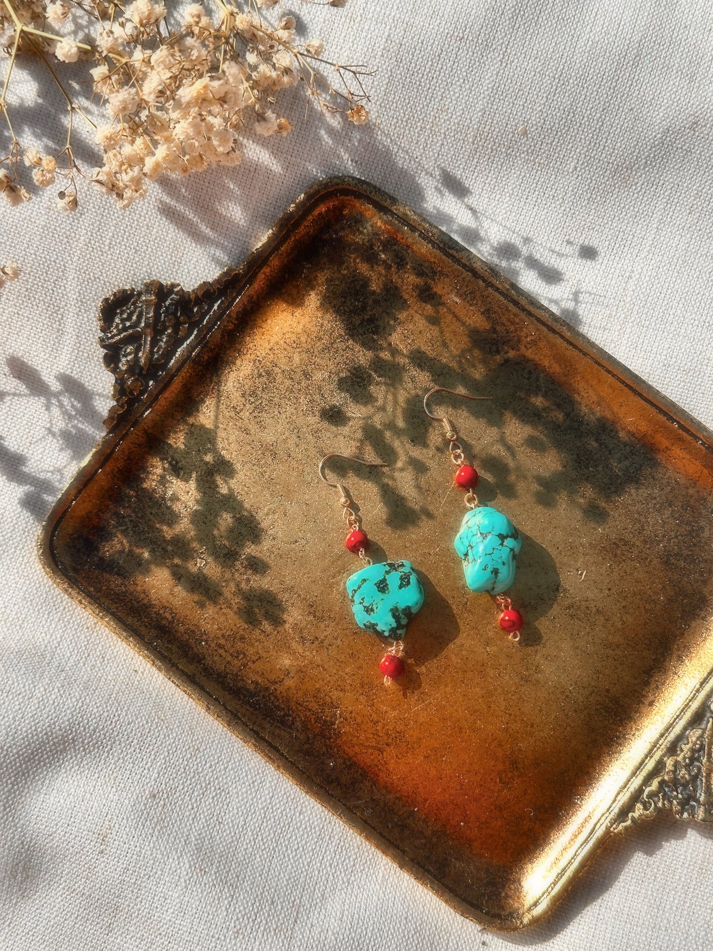 Faux Turquoise and Faux Red Agate beads on a brown and white background. Stainless Steel gold hoops.