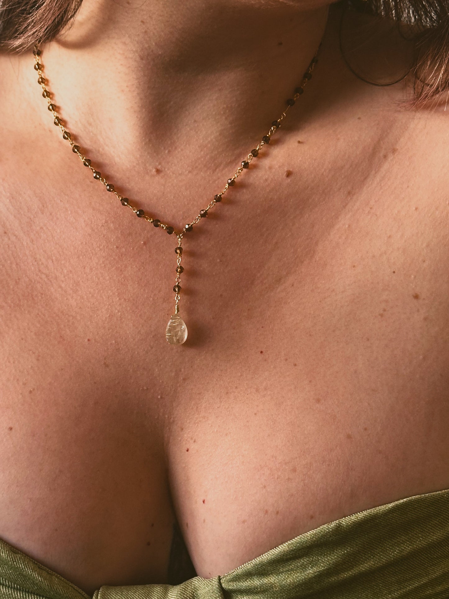 Necklace with a Smoky Quartz and Golden Rutilated Quartz Lariat Style Gold Plated Necklace pendant worn by a person, focusing on the jewelry.