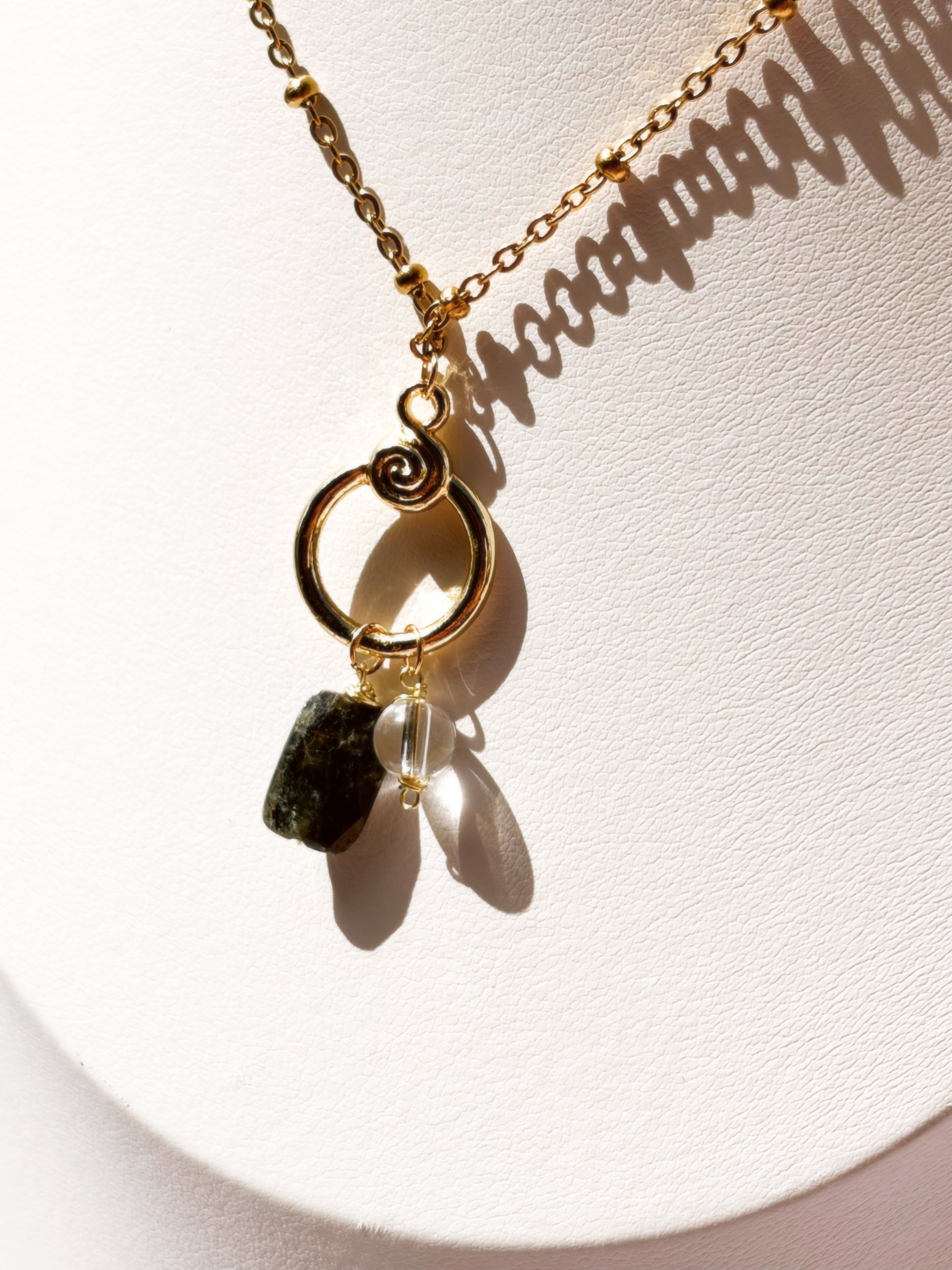 Close up of Gold Stainless Steel necklace with Blue Kyanite and Clear Quartz as a pendant on a white mannequin