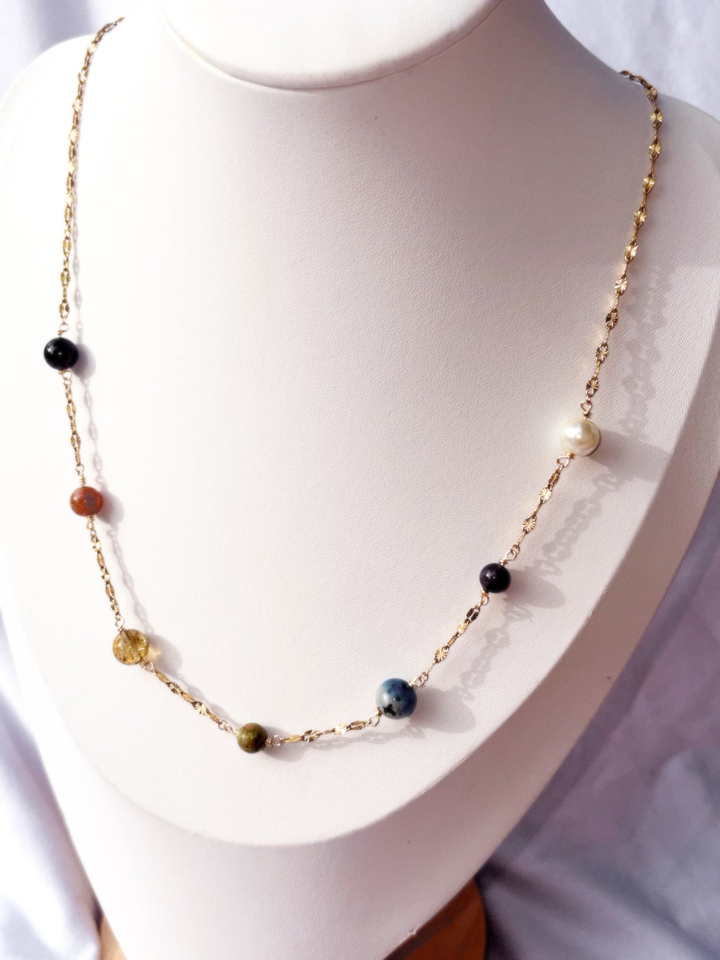 Gold Stainless Steel Necklace with colorful stones on a white stand
