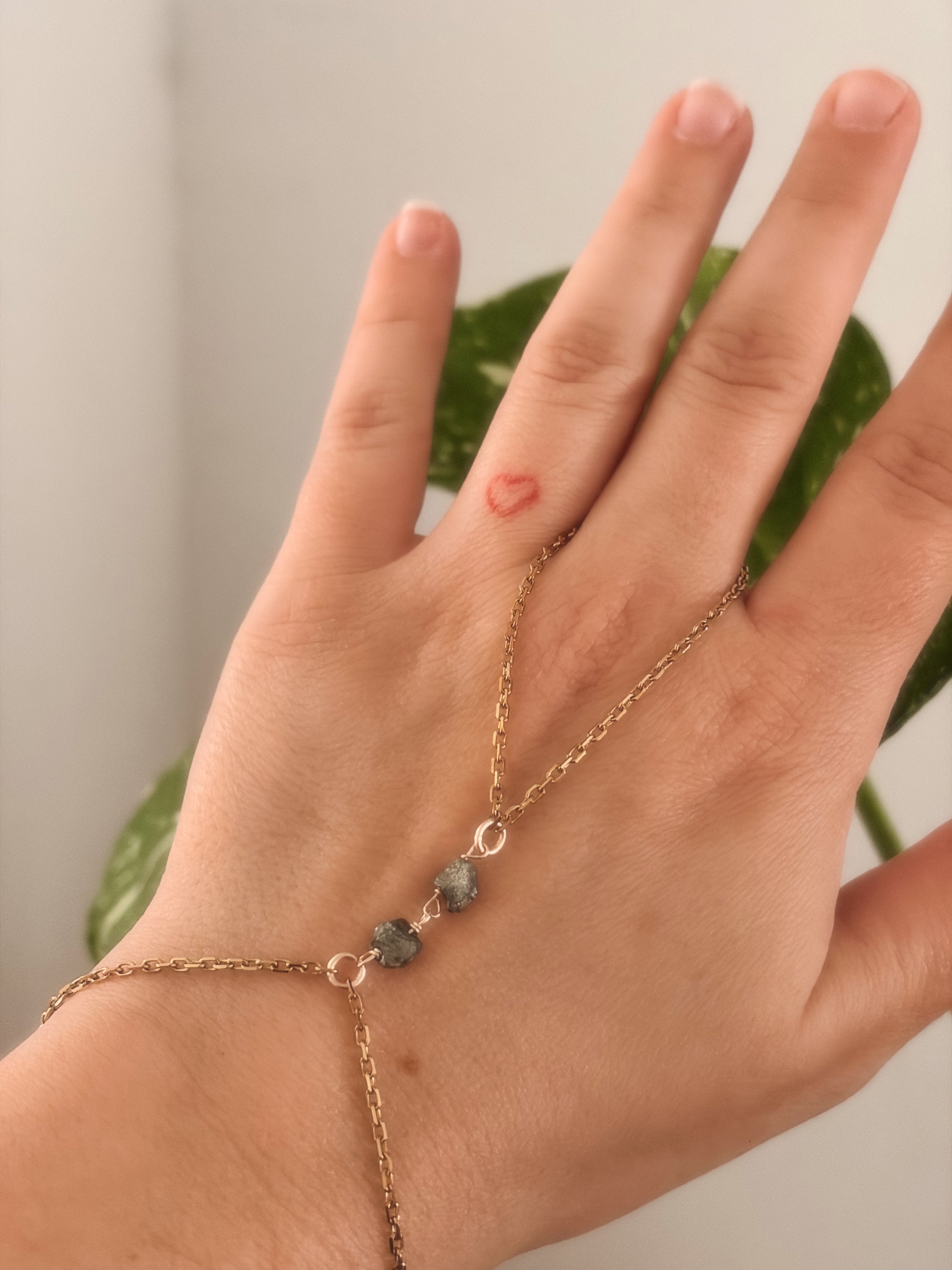 Hand wearing a gold stainless steel bracelet with raw pyrite stones.