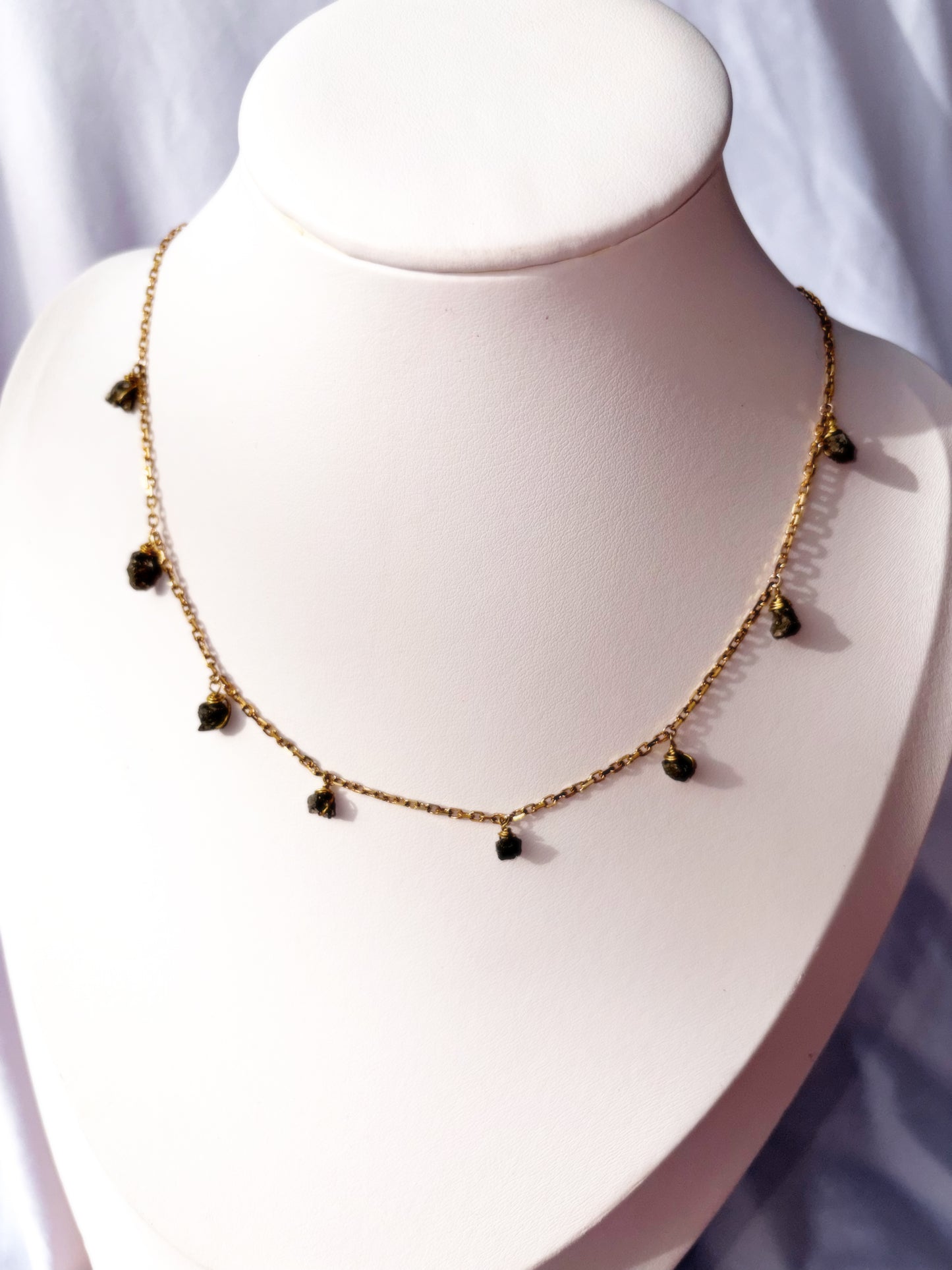 Stainless Steel Gold necklace with small Pyrite raw beads stones on a white stand.