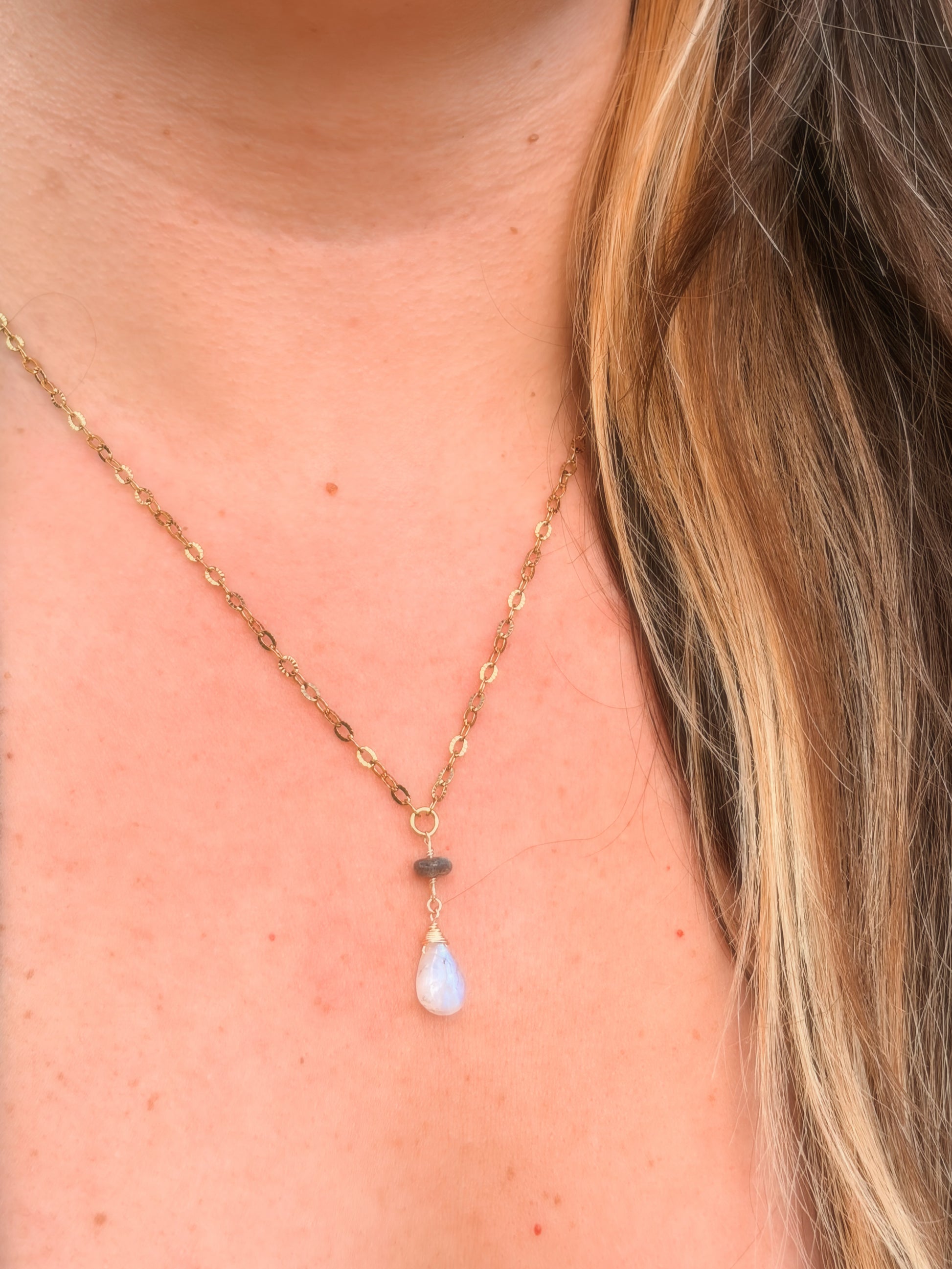 Stainless Steel Gold Necklace with a Labradorite and Rainbow Moonstone pendant on a person's neck.