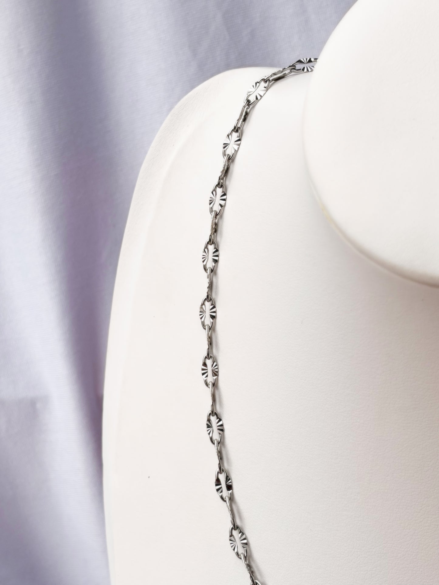 Silver necklace on a white necklace holder with a white background