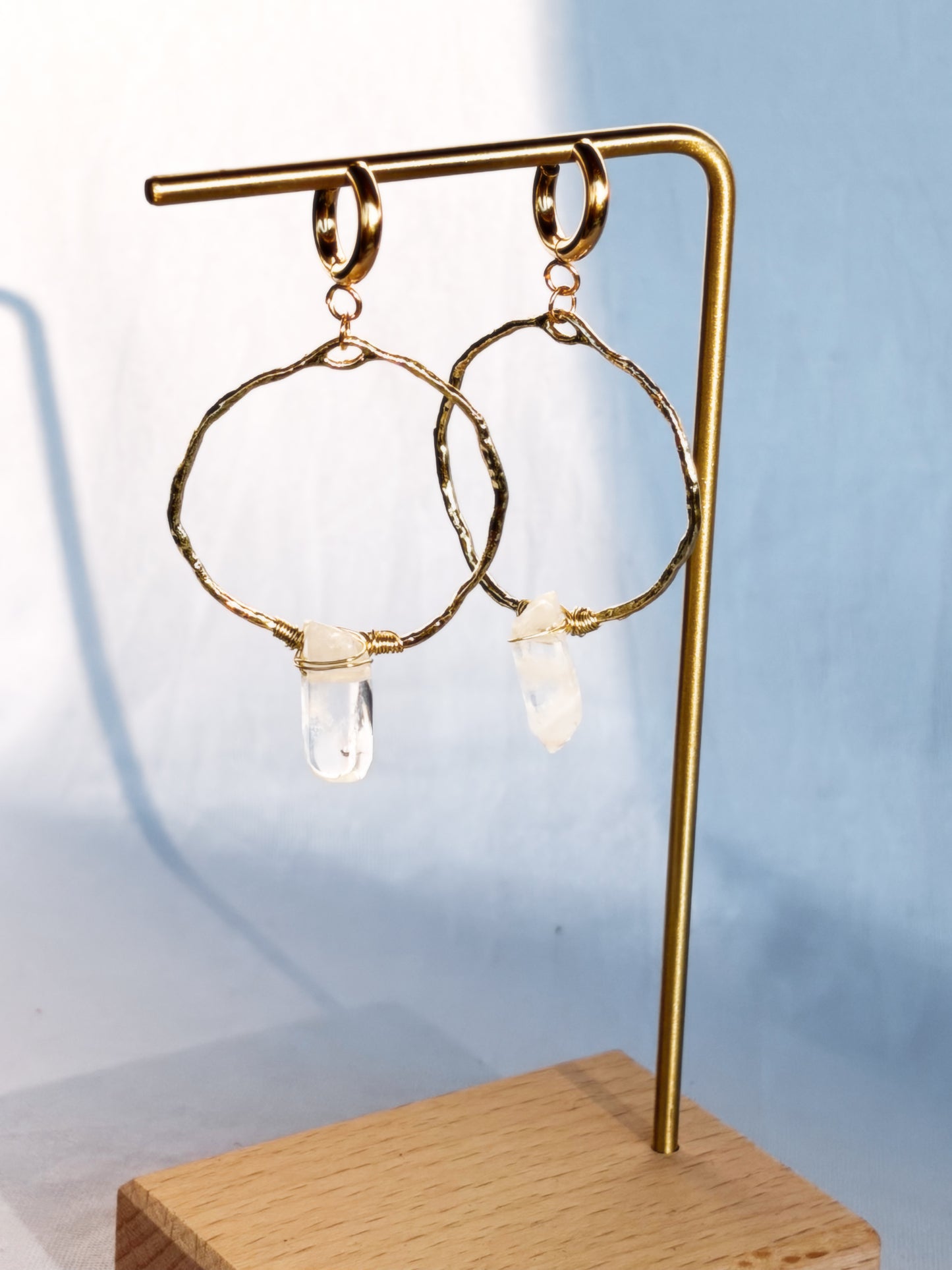 Gold Hoop earring with clear quartz gemstones on a light background