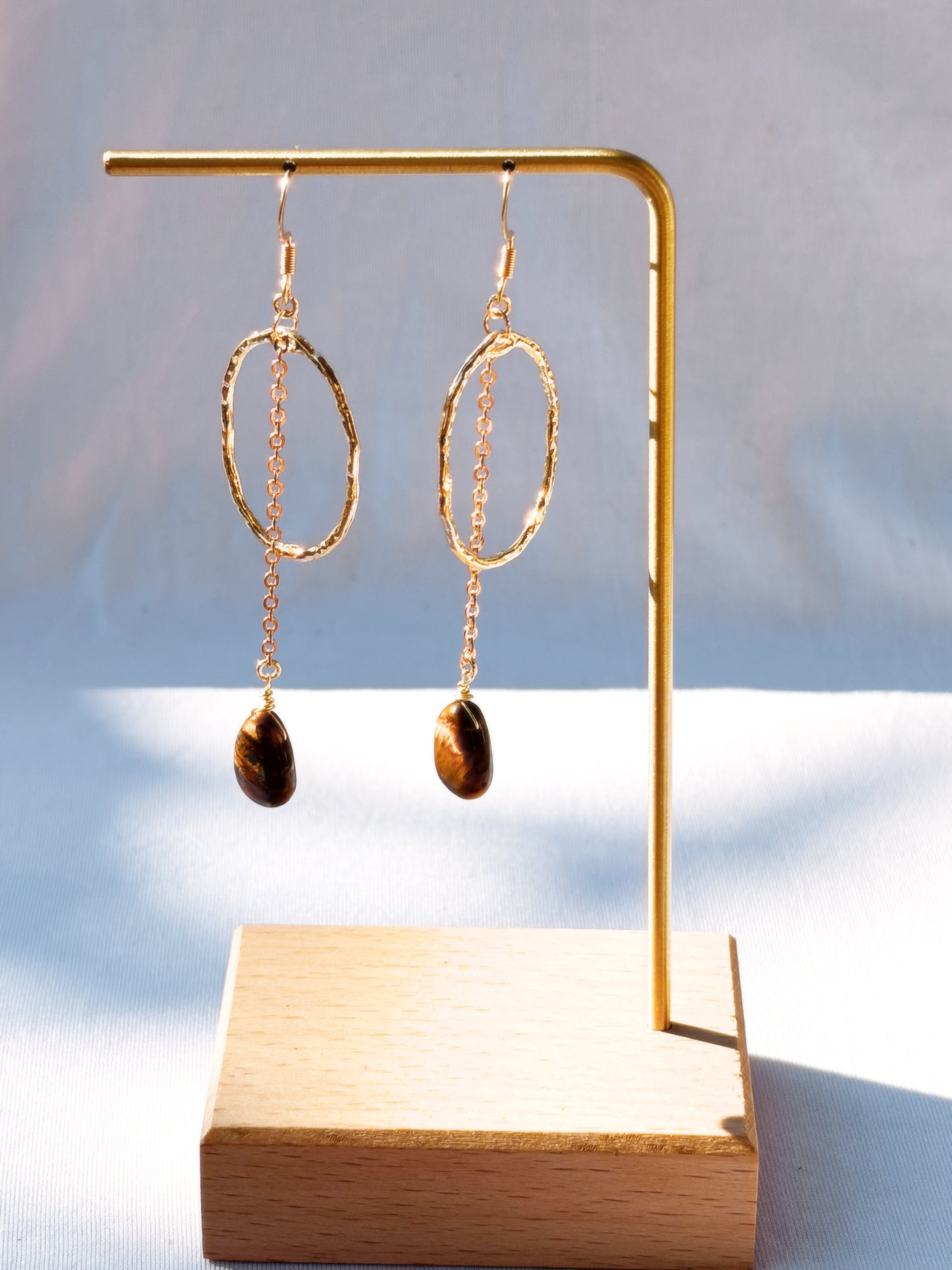 Stainless Steel Hoop Earrings Golden Rutilated Quartz and Tiger Eye pair of earrings with beads on a light background