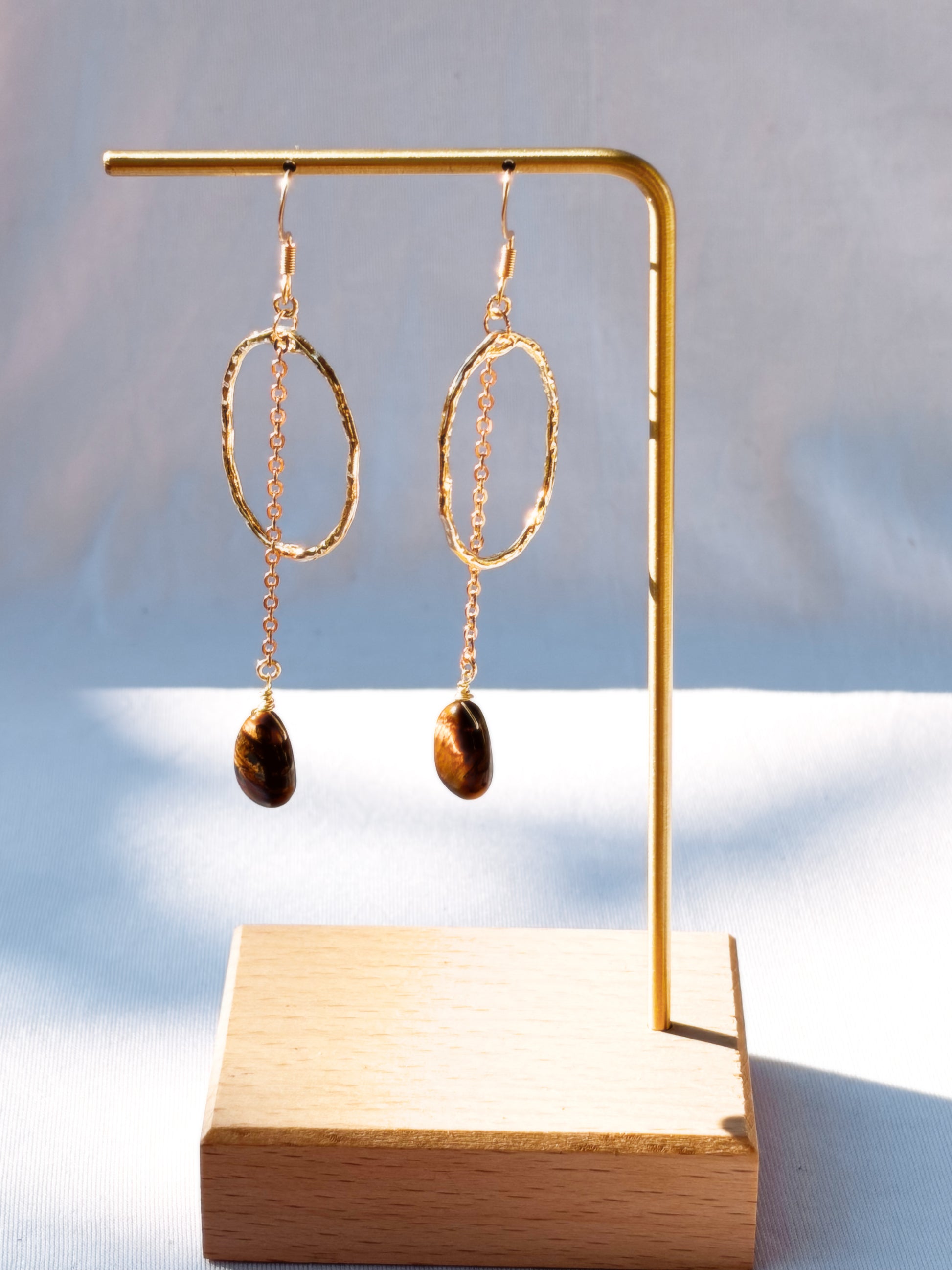 Stainless Steel Hoop Earrings Golden Rutilated Quartz and Tiger Eye pair of earrings with beads on a light background