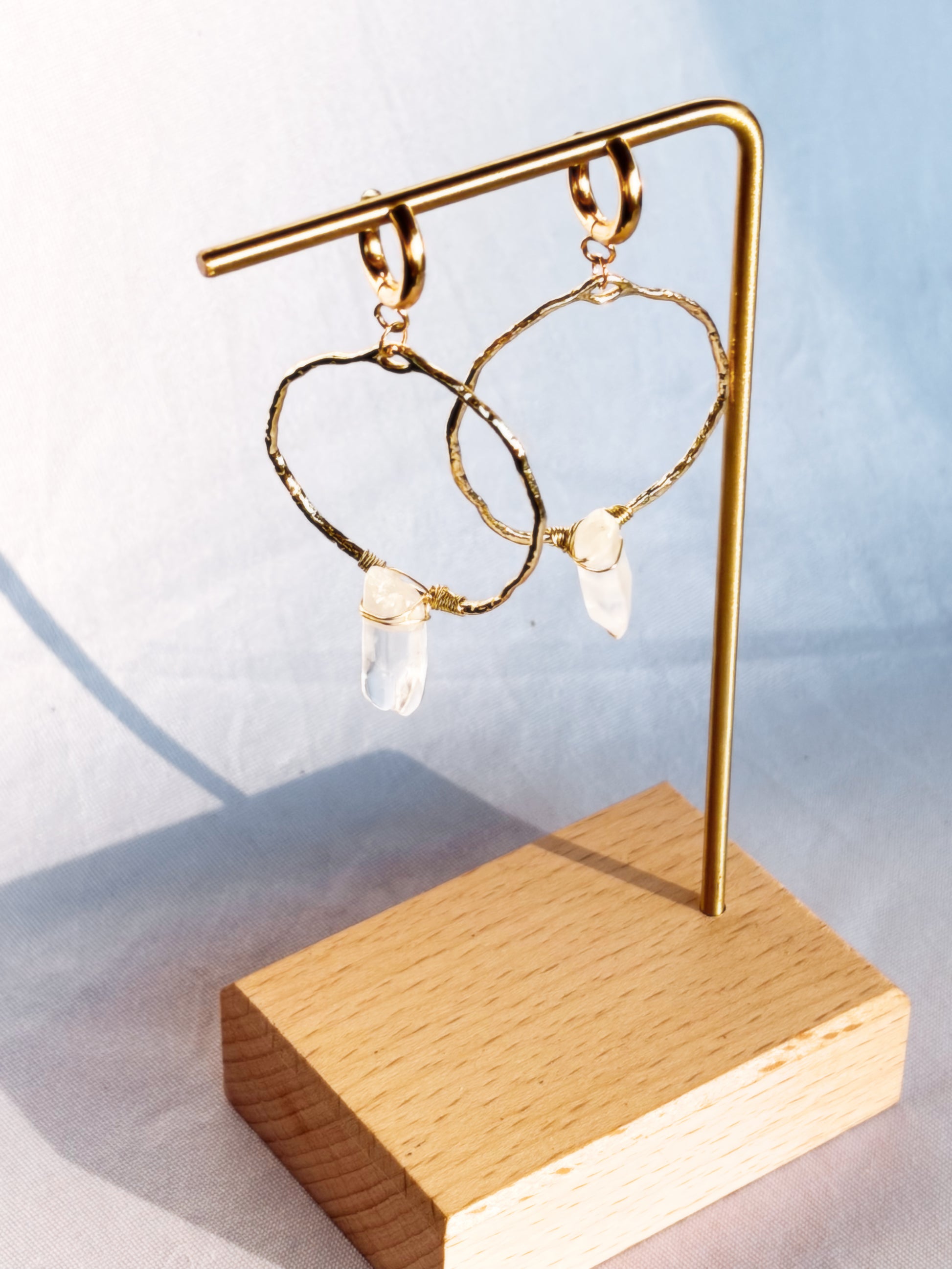 Gold Hoop earring with clear quartz gemstones on a light background