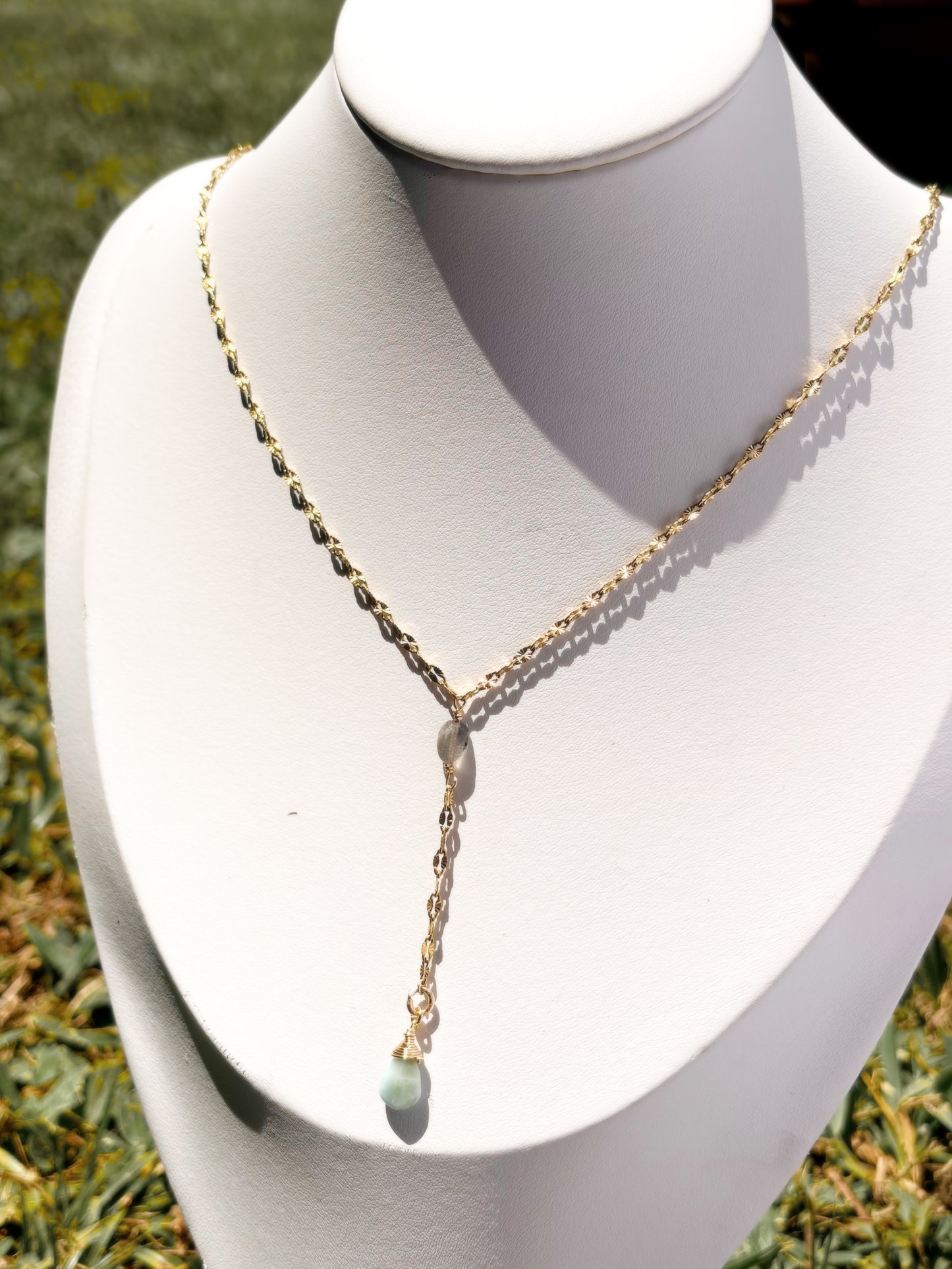 A delicate gold Y-necklace with a small Labradorite and Larimar pendants on a white bust.