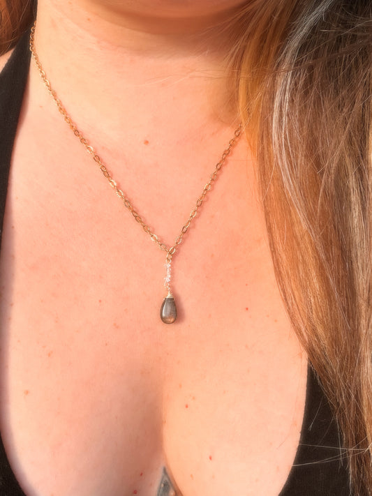 Close-up of a Gold Stainless Steel  necklace with a Labradorite pendant on a person's neck.