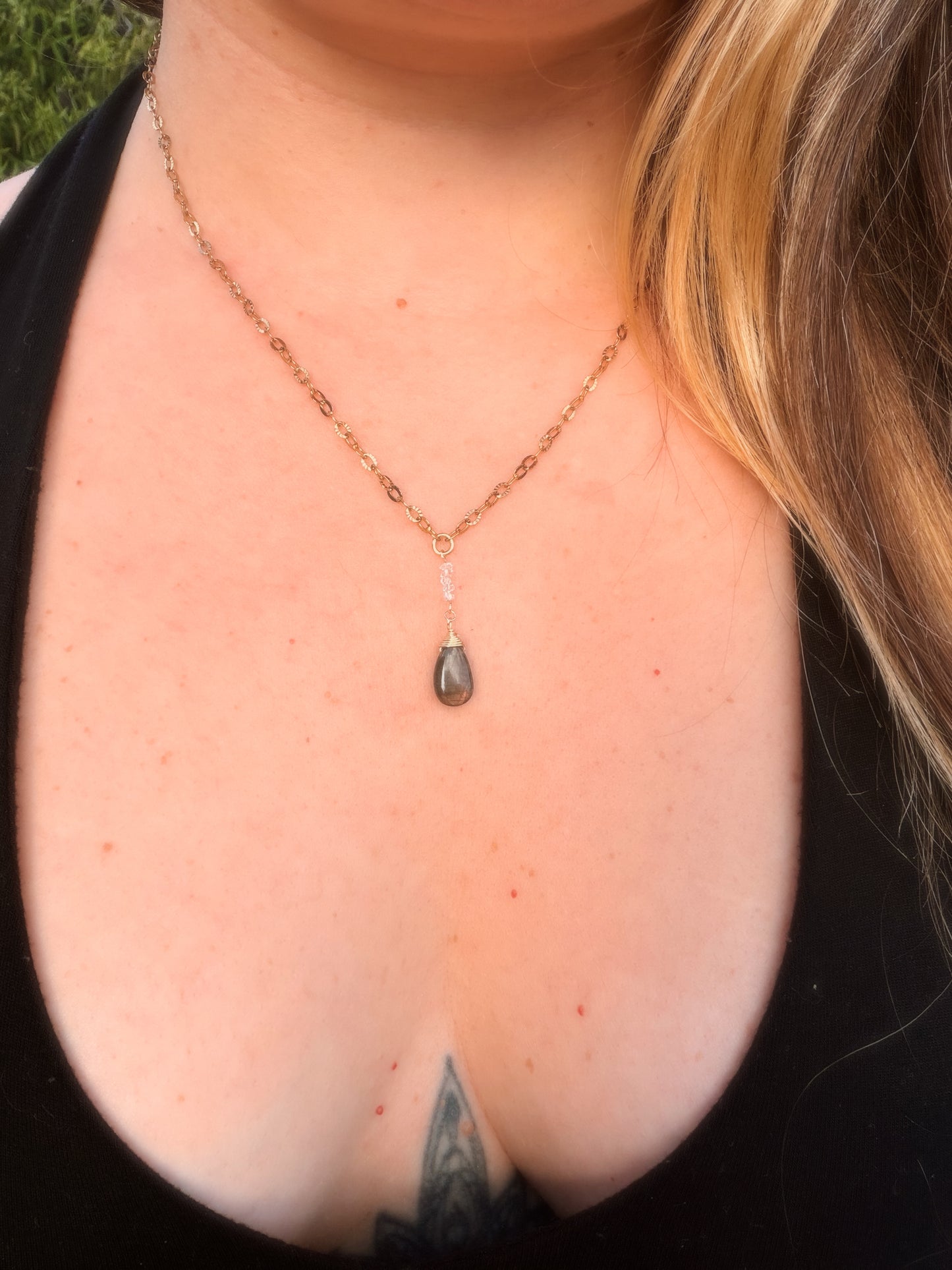 Close-up of a Gold Stainless Steel  necklace with a Labradorite pendant on a person's neck.