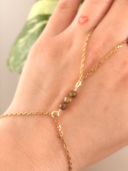 Gold Stainless Steel tarnish resistant handchain with Green Garnet crystal beads on a person's hand.