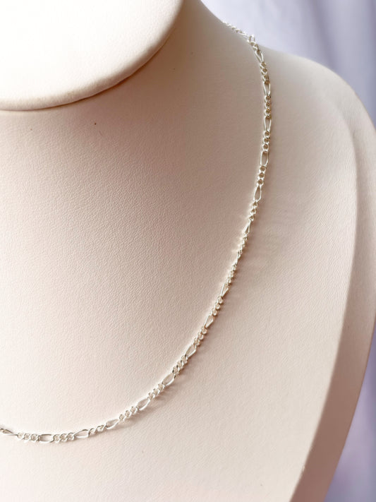 Close up of Figaro Silver chain Necklace on a white mannequin bust and background.