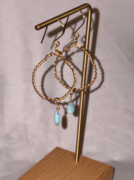 Gold brass and stainless steel hoop earrings with turquoise Larimar stones on a light background.
