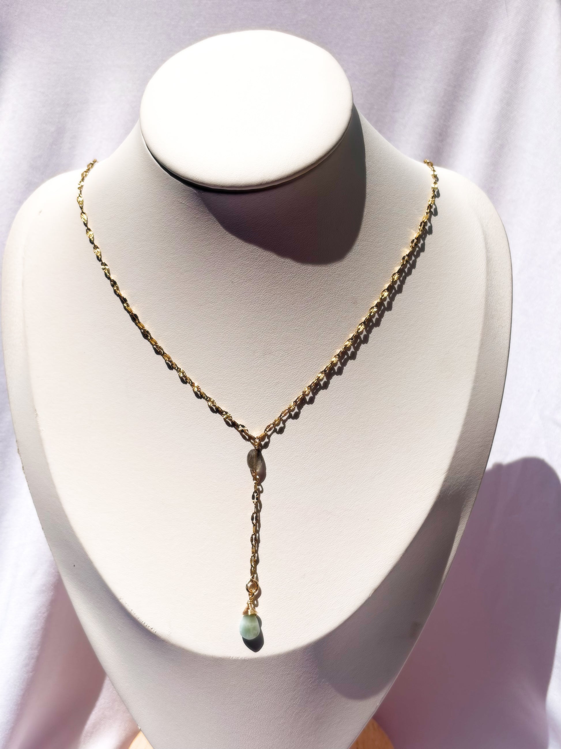 A delicate gold Y-necklace with a small Labradorite and Larimar pendants on a white bust.