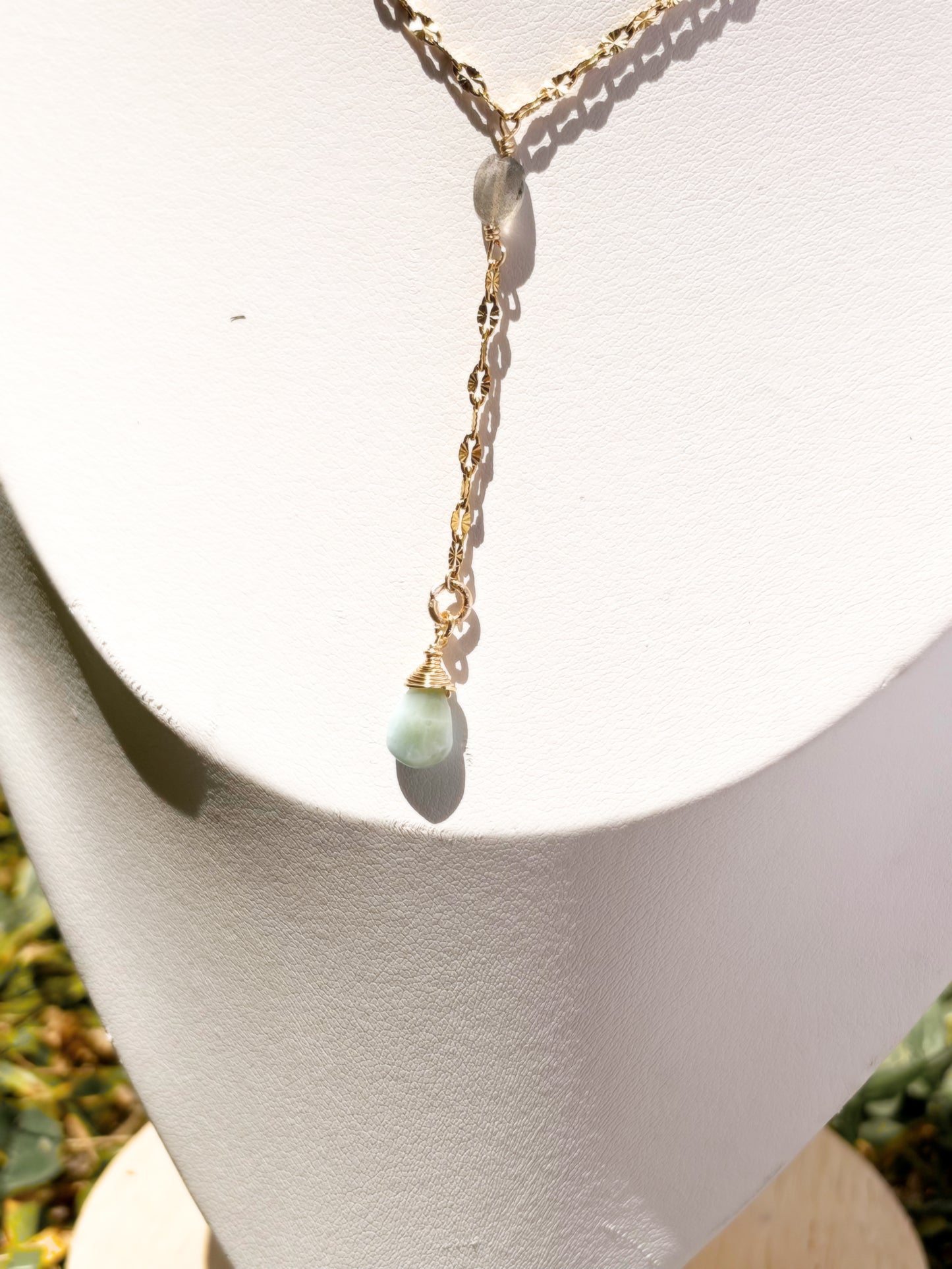 A delicate gold Y-necklace with a small Labradorite and Larimar pendants on a white bust.