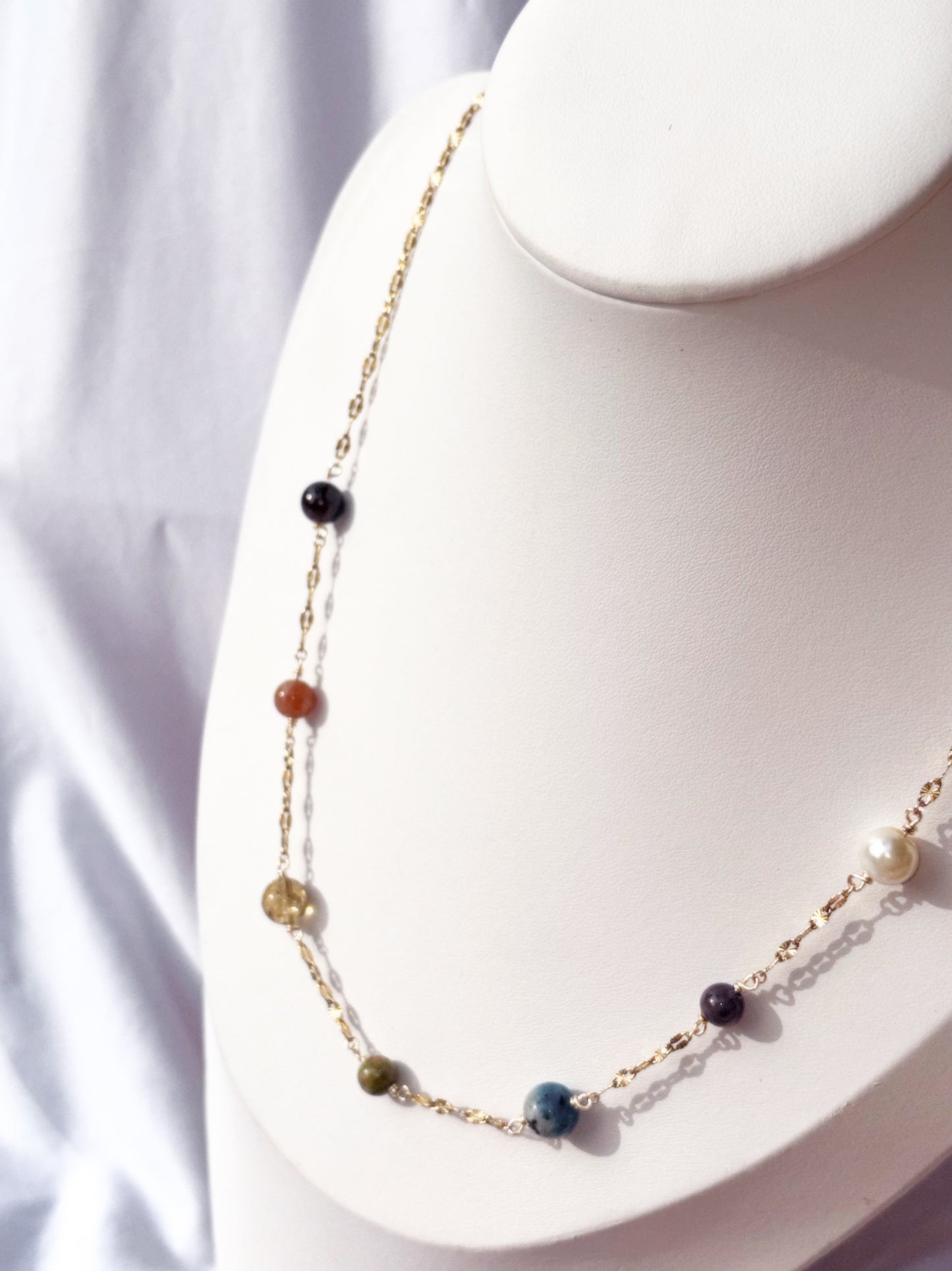 Gold Stainless Steel Necklace with colorful stones on a white stand