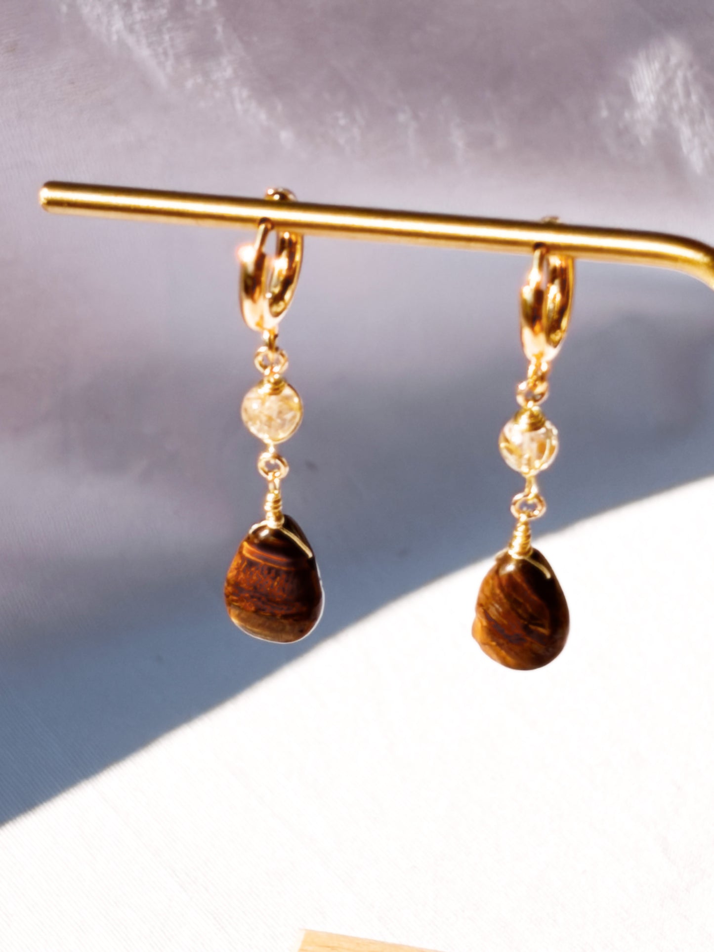 Golden Rutilated Quartz and Tiger Eye pair of earrings with beads on a light background