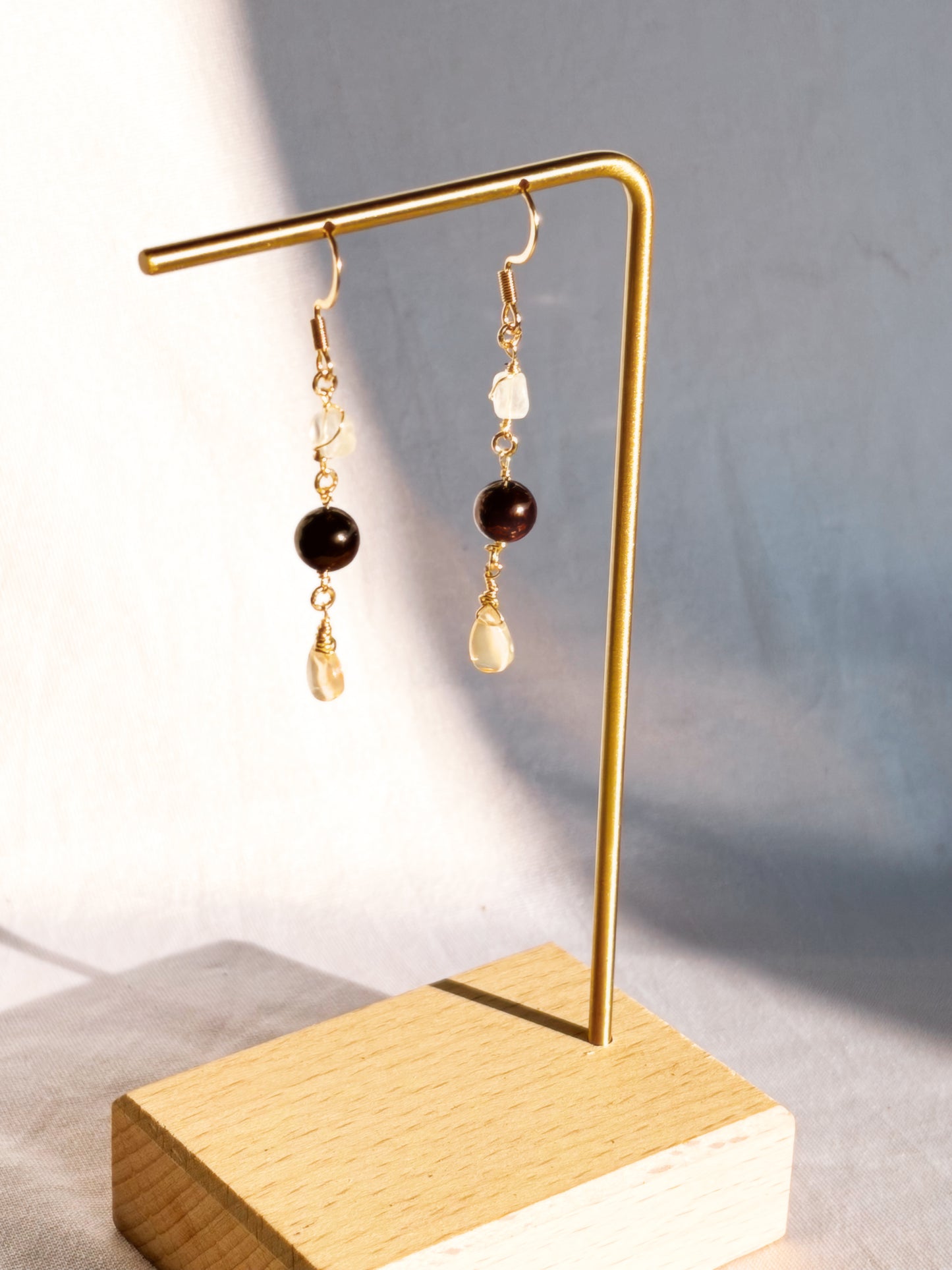 Gold Stainless Steel with Rainbow Moonstone, Ethiopian Opal and Garnet crystals on a gold stand against a neutral background