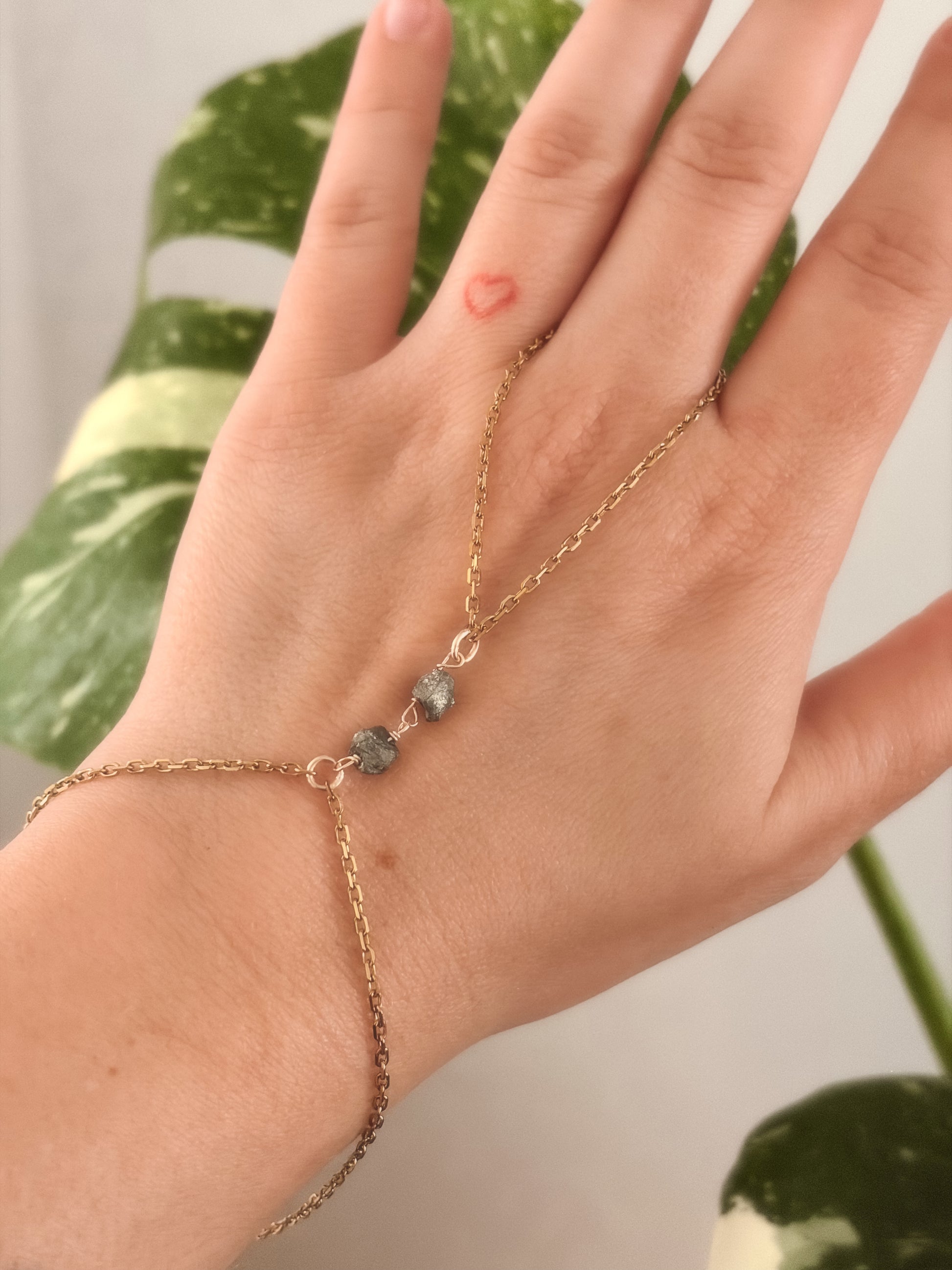Hand wearing a gold stainless steel bracelet with raw pyrite stones on a persons hand.
