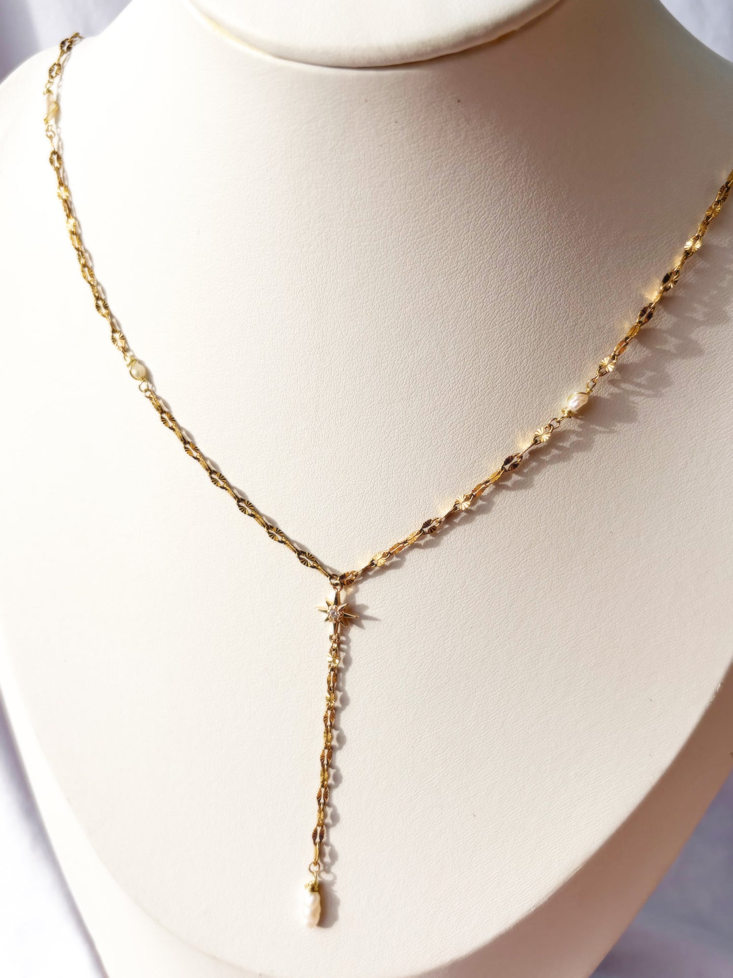 Gold Stainless Steel Faux Pearl chain necklace with a sunburst charm on a mannequin bust against a white background