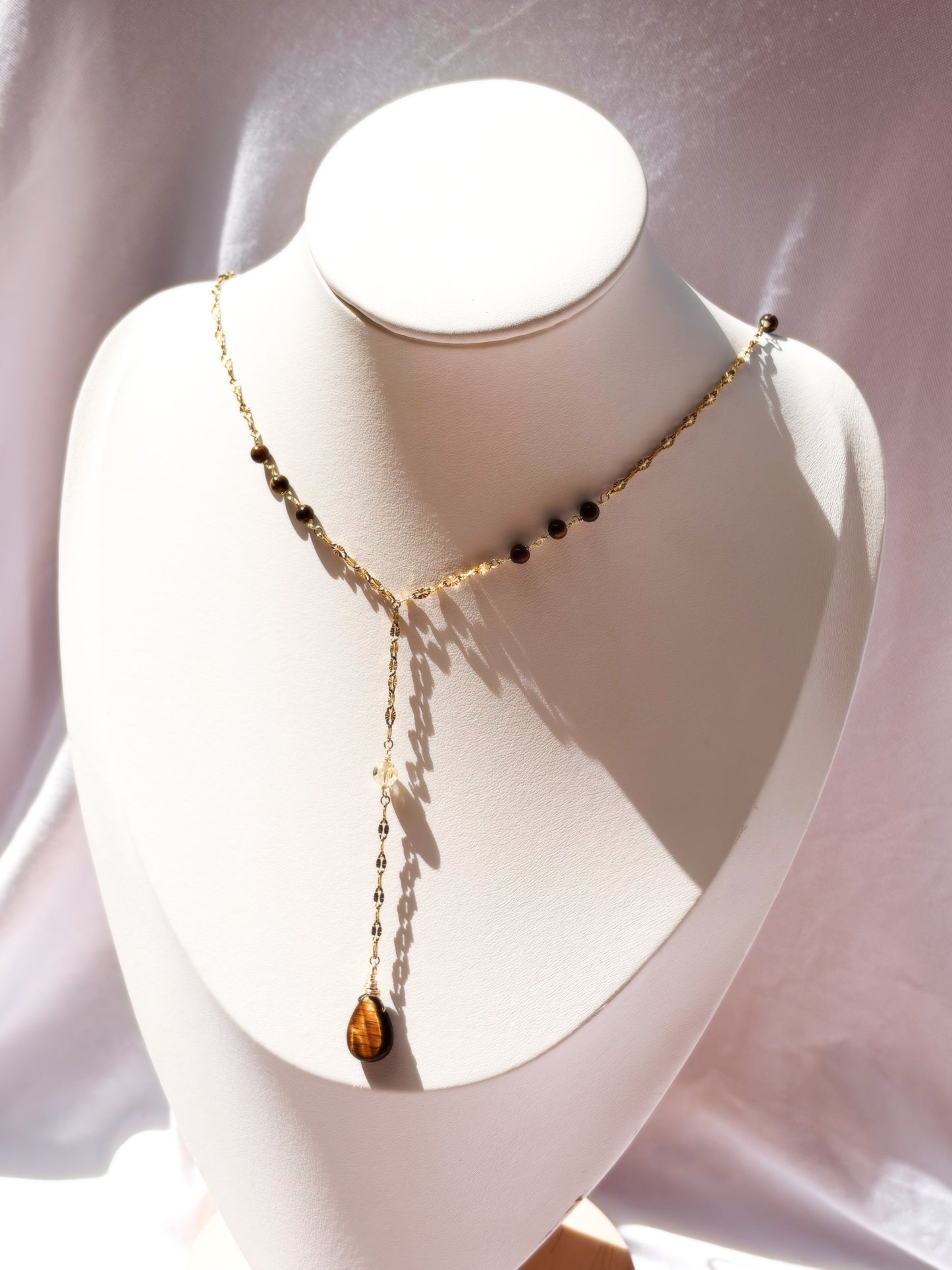 Gold Stainless Steel Lip Chain necklace with Tiger Eye beads on a white stand against a light background