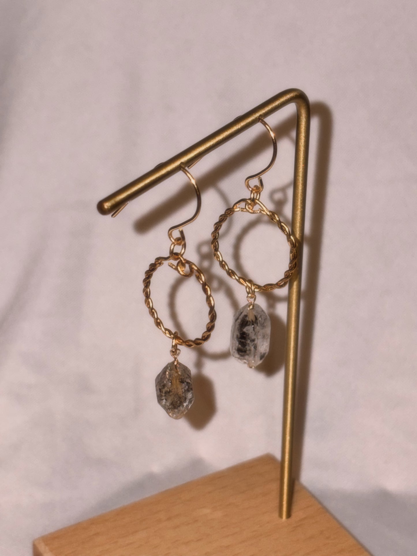 Gold hoop earrings with Herkimer Crystal  drops on a gold stand against a white background