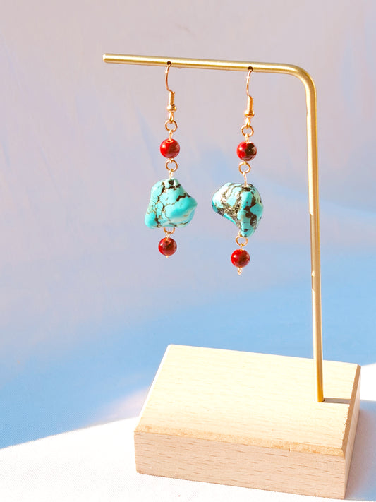 Gold earrings with turquoise and red beads on a white background