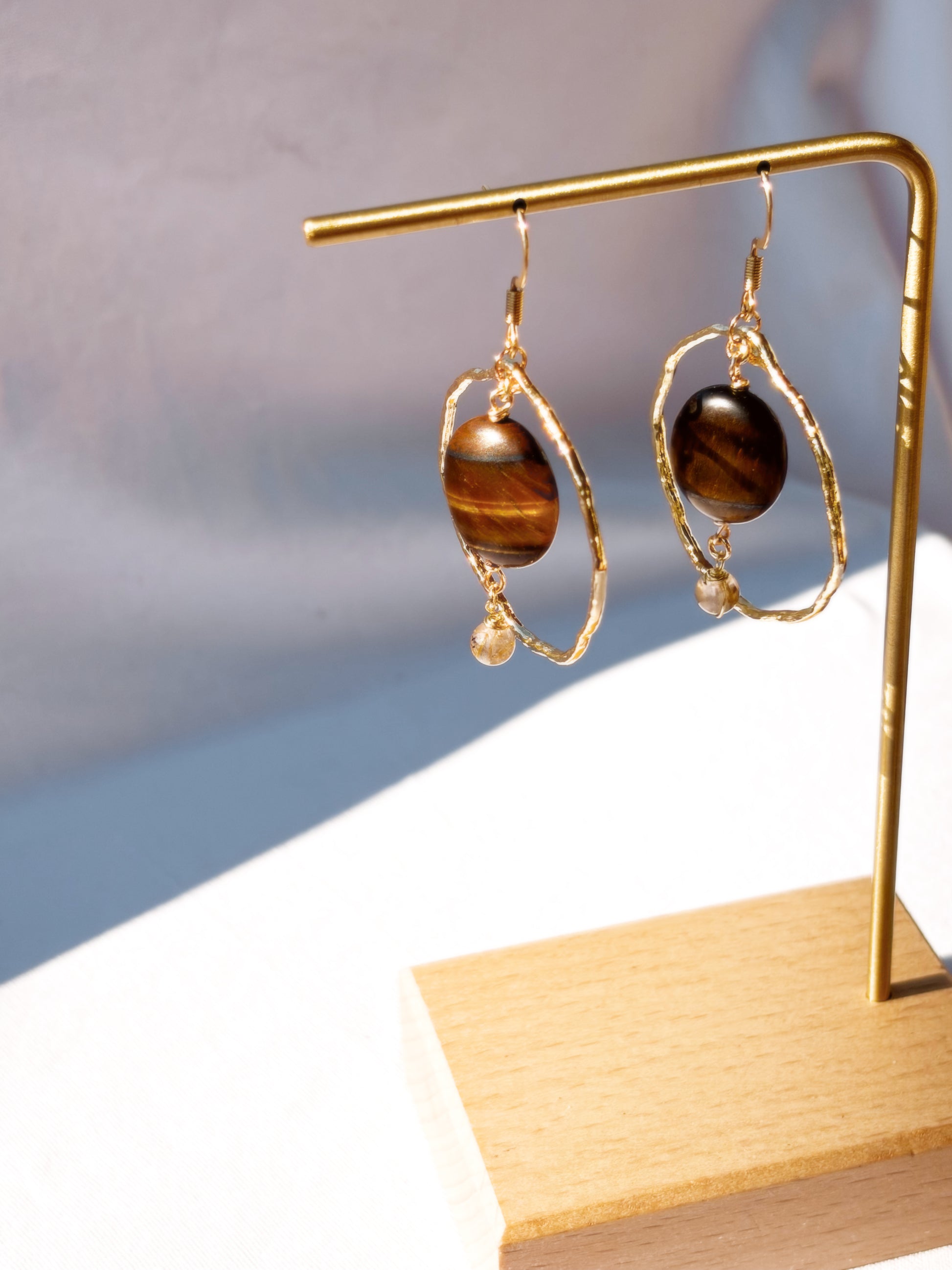 Stainless Steel Golden Rutilated Quartz and Tiger Eye pair of earrings with beads on a light background