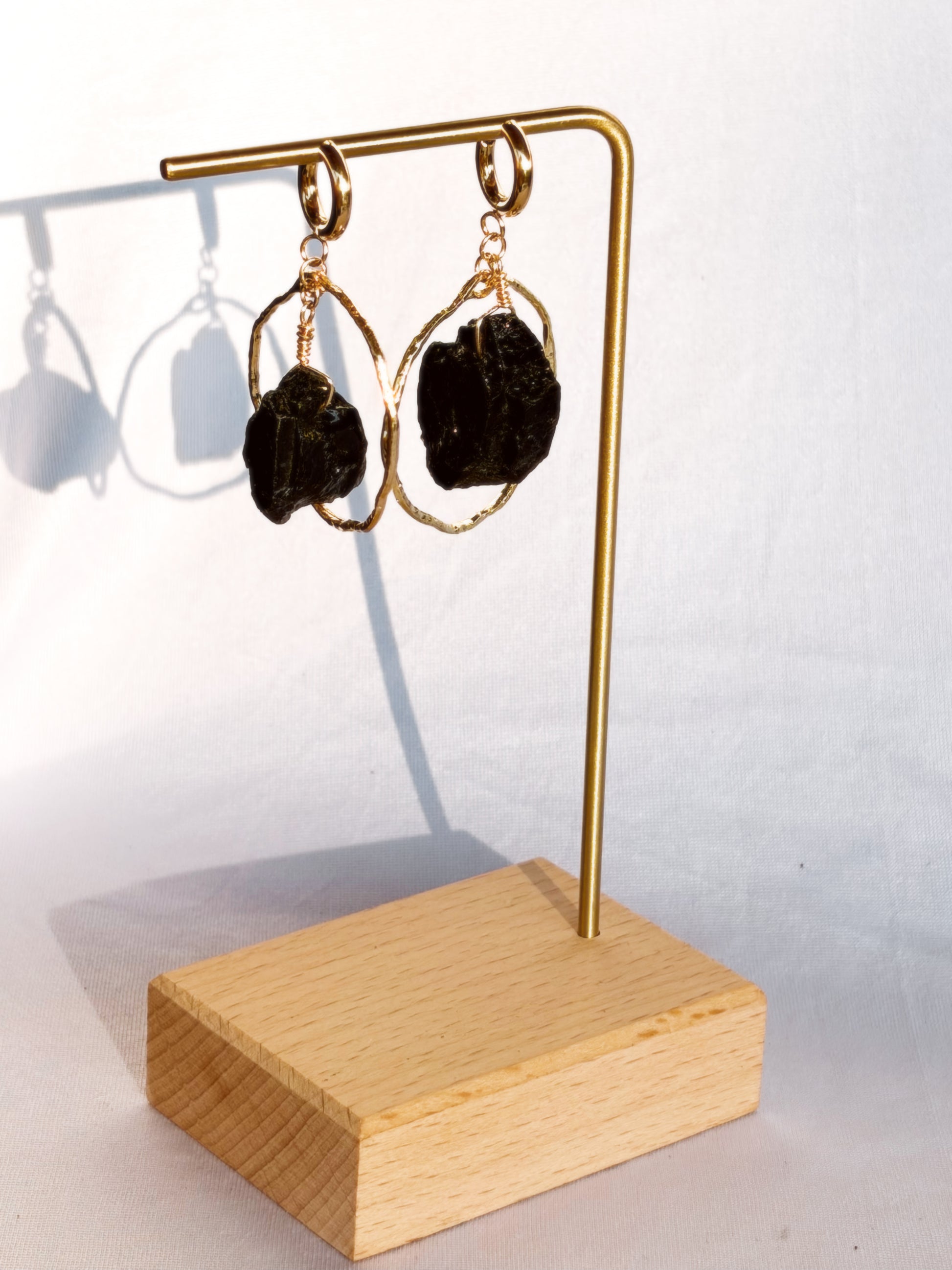 Gold earrings with Black Tourmaline stones on a white background.