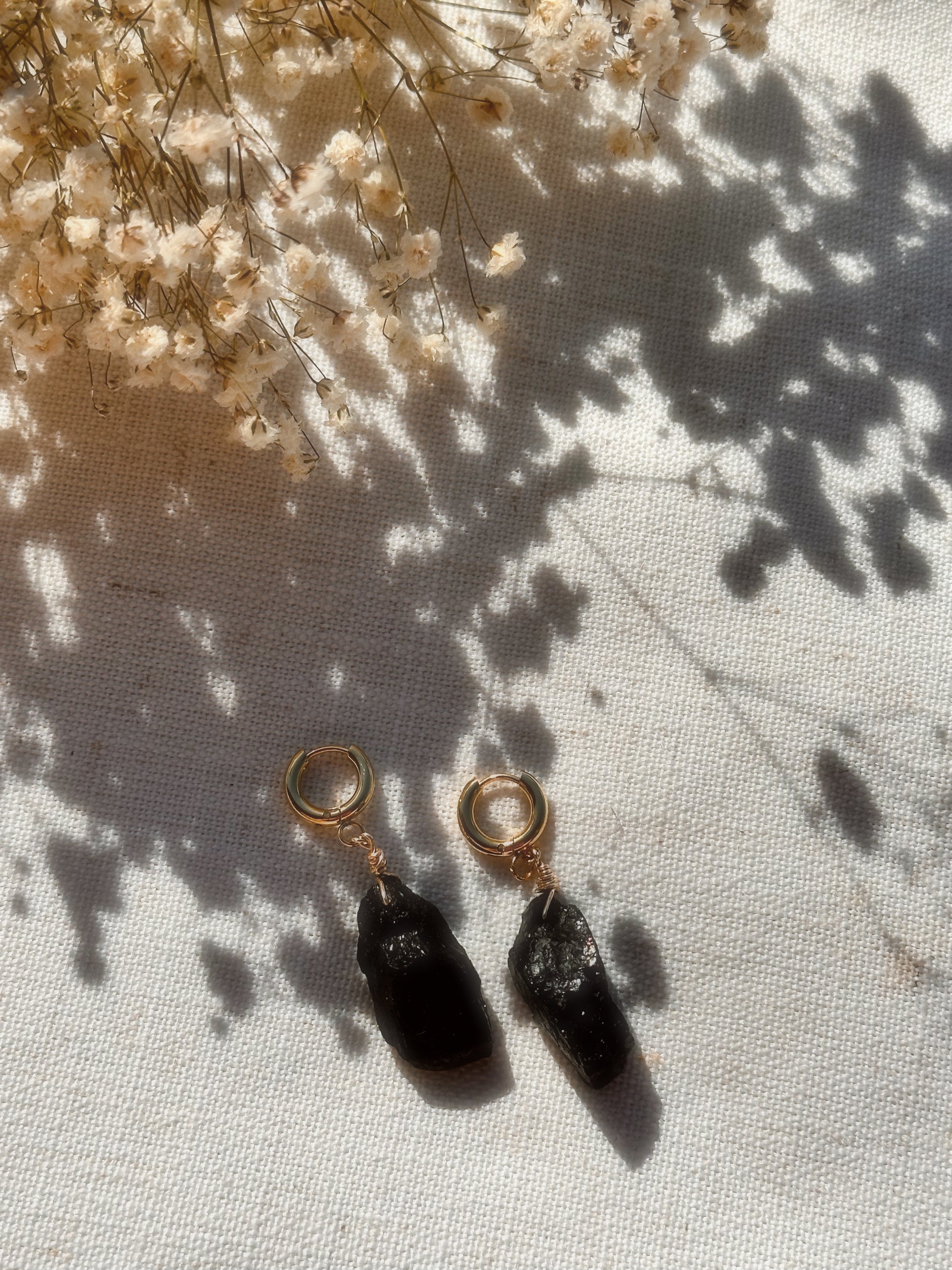 Gold Stainless Steel earrings with Black Tourmaline stones on a white background.