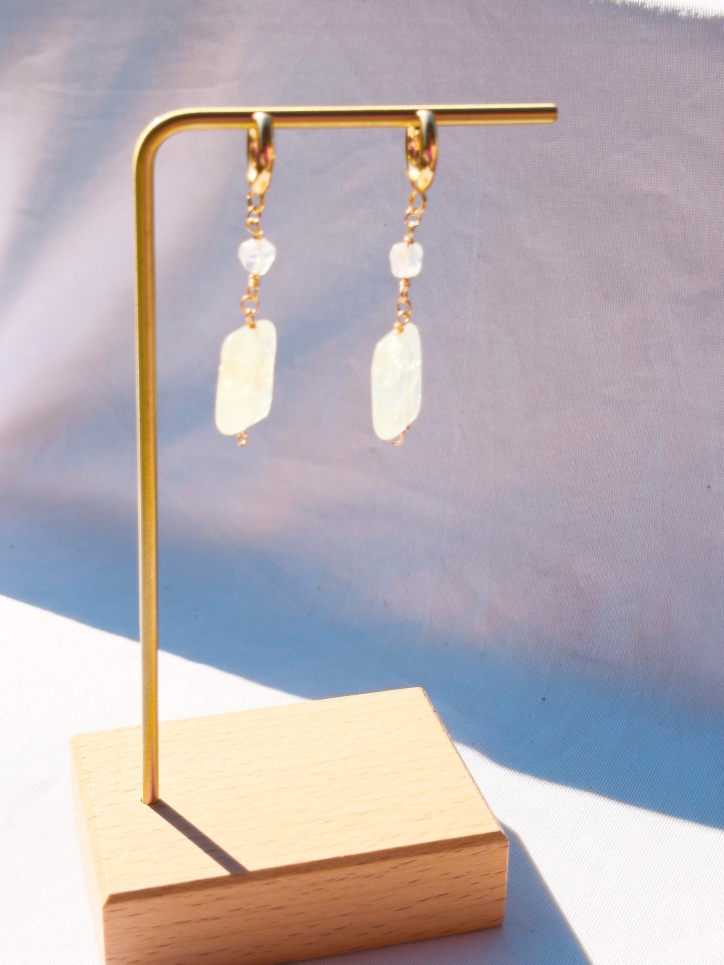 Gold earrings with Rainbow Moonstone and Prehnite crystals on a light background
