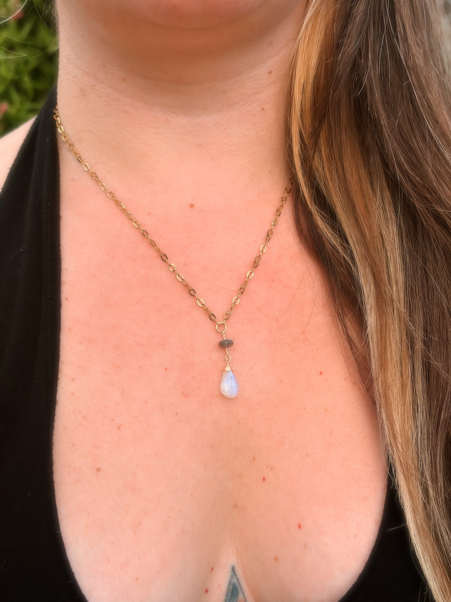 Stainless Steel Gold Necklace with a Labradorite and Rainbow Moonstone pendant on a person's neck.