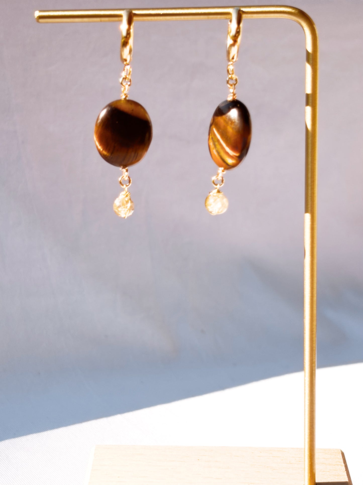 Golden Rutilated Quartz and Tiger Eye pair of earrings with beads on a light background