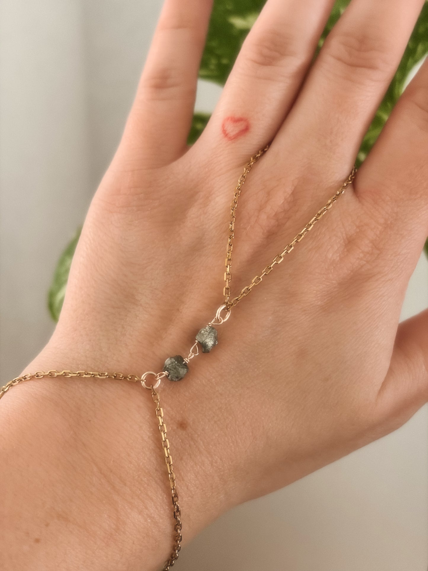 Hand wearing a gold stainless steel bracelet with raw pyrite stones.