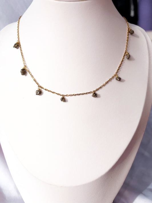 Stainless Steel Gold necklace with small Pyrite raw beads stones on a white stand.