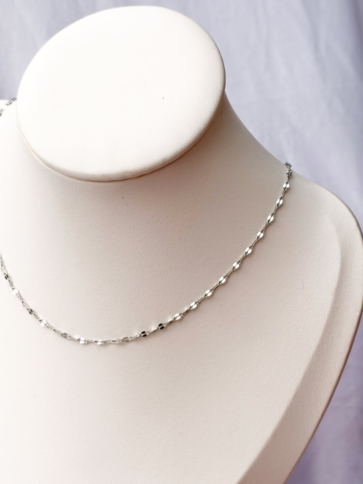 Silver chain on a mannequin bust with a white background
