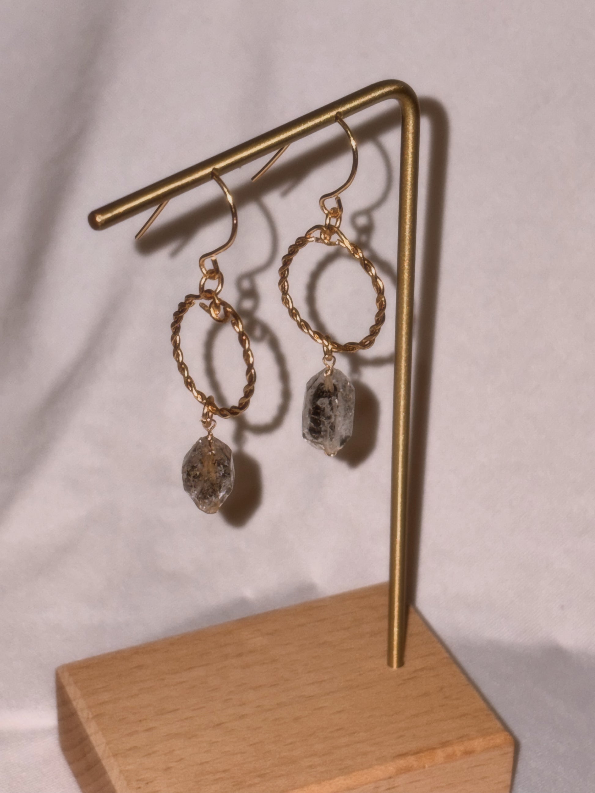 Gold hoop earrings with Herkimer Crystal  drops on a gold stand against a white background