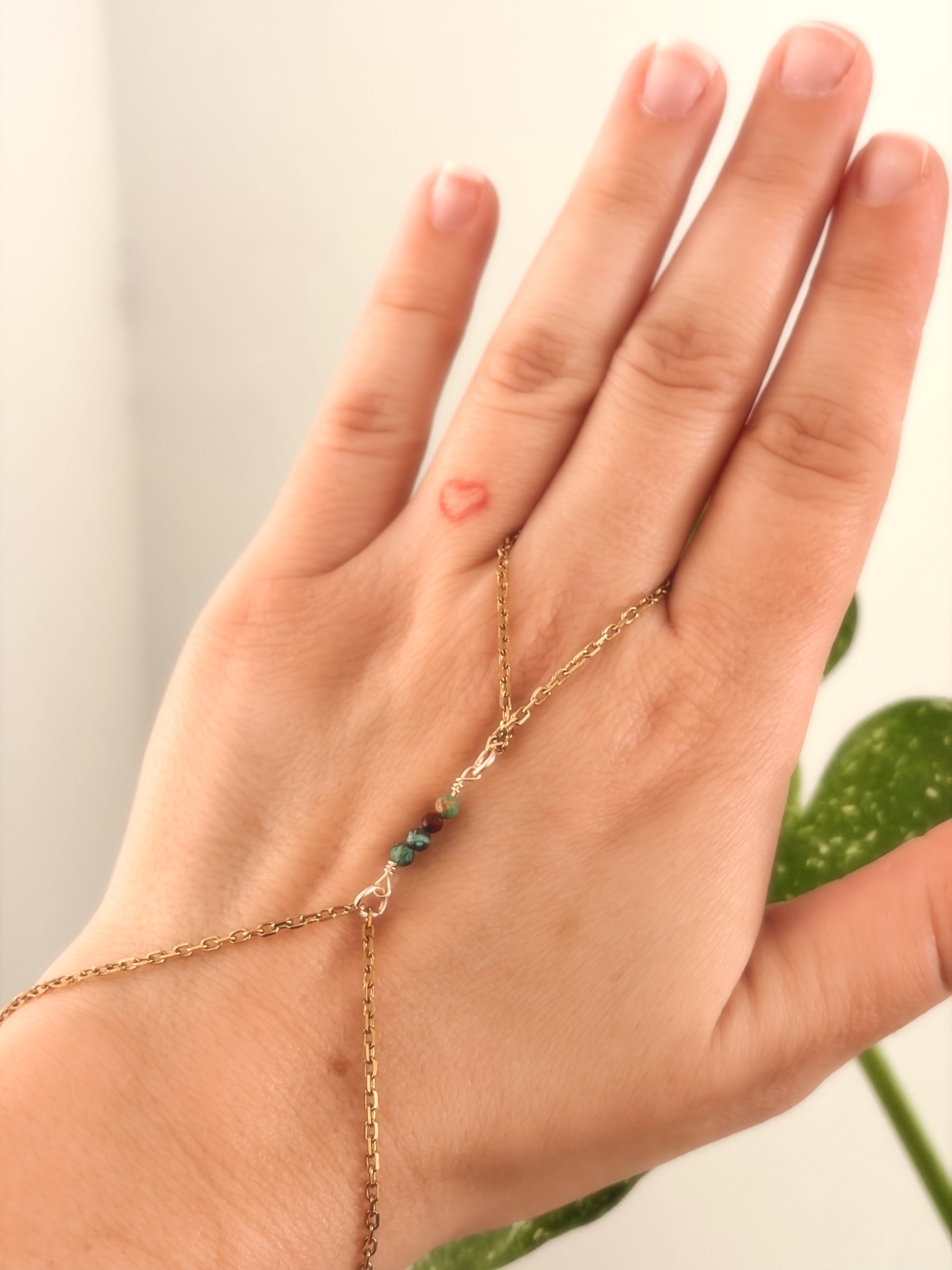 Hand wearing a gold bracelet with turquoise stones on a light background