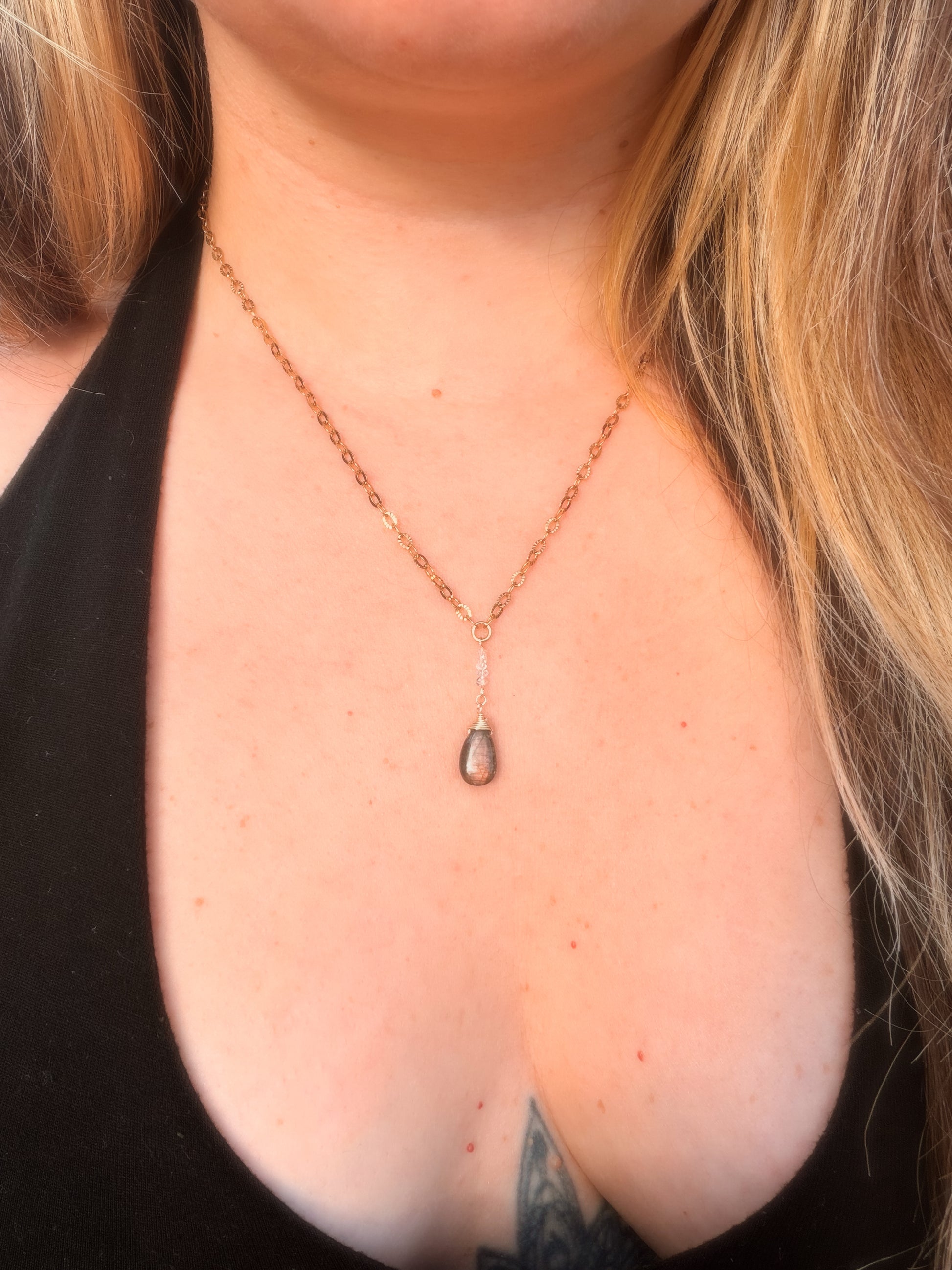 Close-up of a Gold Stainless Steel  necklace with a Labradorite pendant on a person's neck.