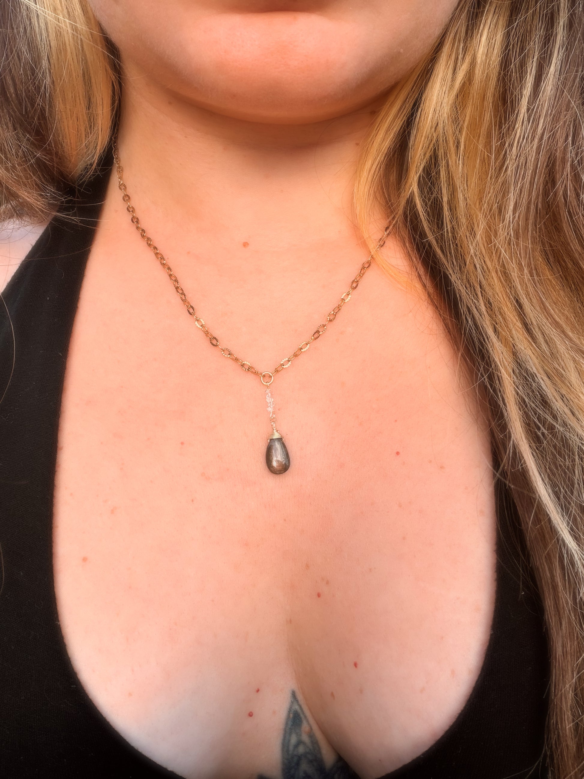 Close-up of a Gold Stainless Steel  necklace with a Labradorite pendant on a person's neck.