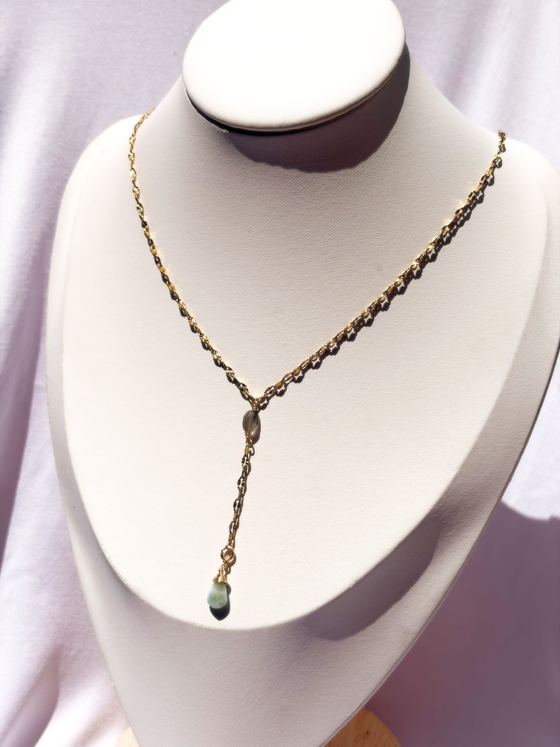 A delicate gold Y-necklace with a small Labradorite and Larimar pendants on a white bust.