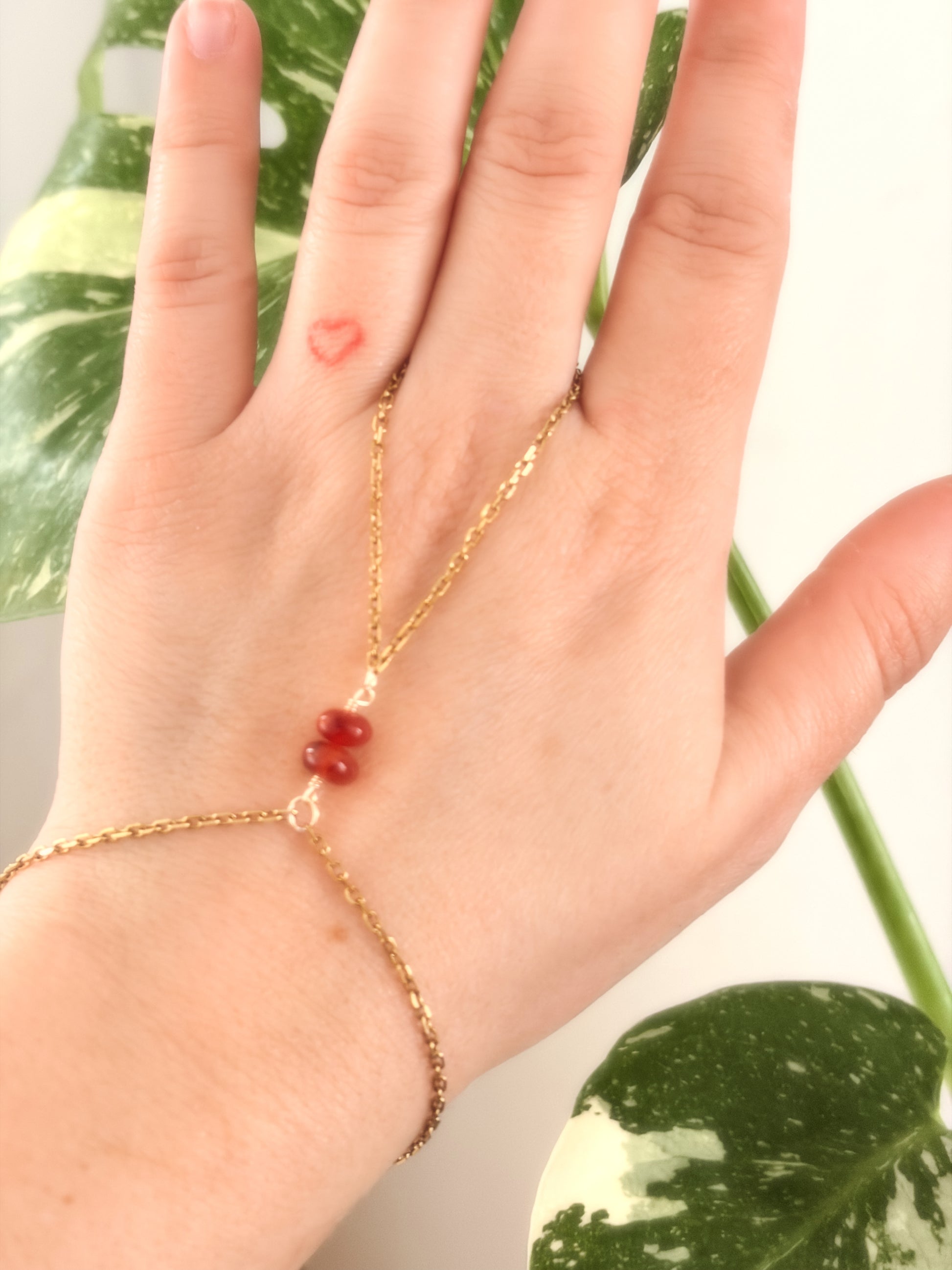 Gold Stainless Steel tarnish resistant handchain with Carnelian crystal beads on a person's hand.