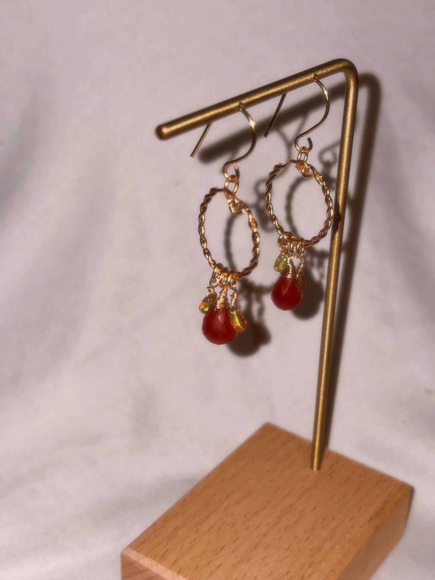 Gold brass and stainless steel hoop earrings with Carnelian and Ethiopian Opal beads on a white background.
